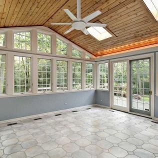 Bright sunroom with tall windows, wood ceiling, ceiling fan, and tiled floor.