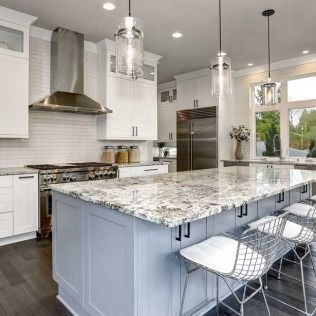 Bright modern kitchen with a large marble island, white cabinets, stainless steel appliances, and pendant lights