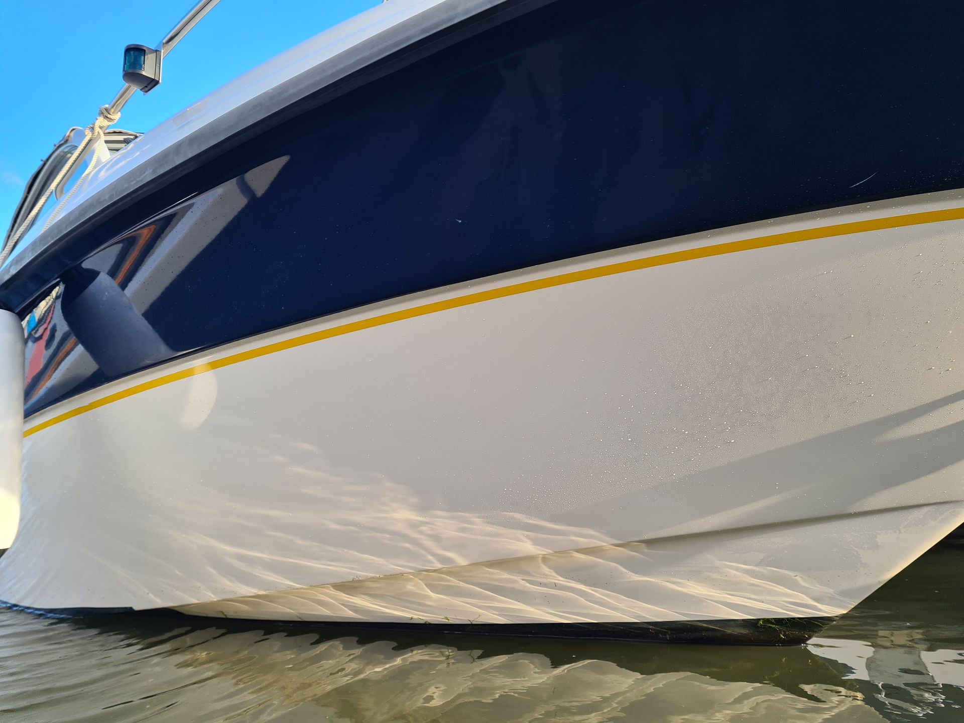 A blue and white boat is floating on top of a body of water.
