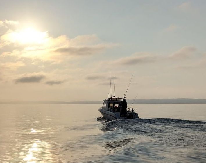 A boat riding in the setting sun