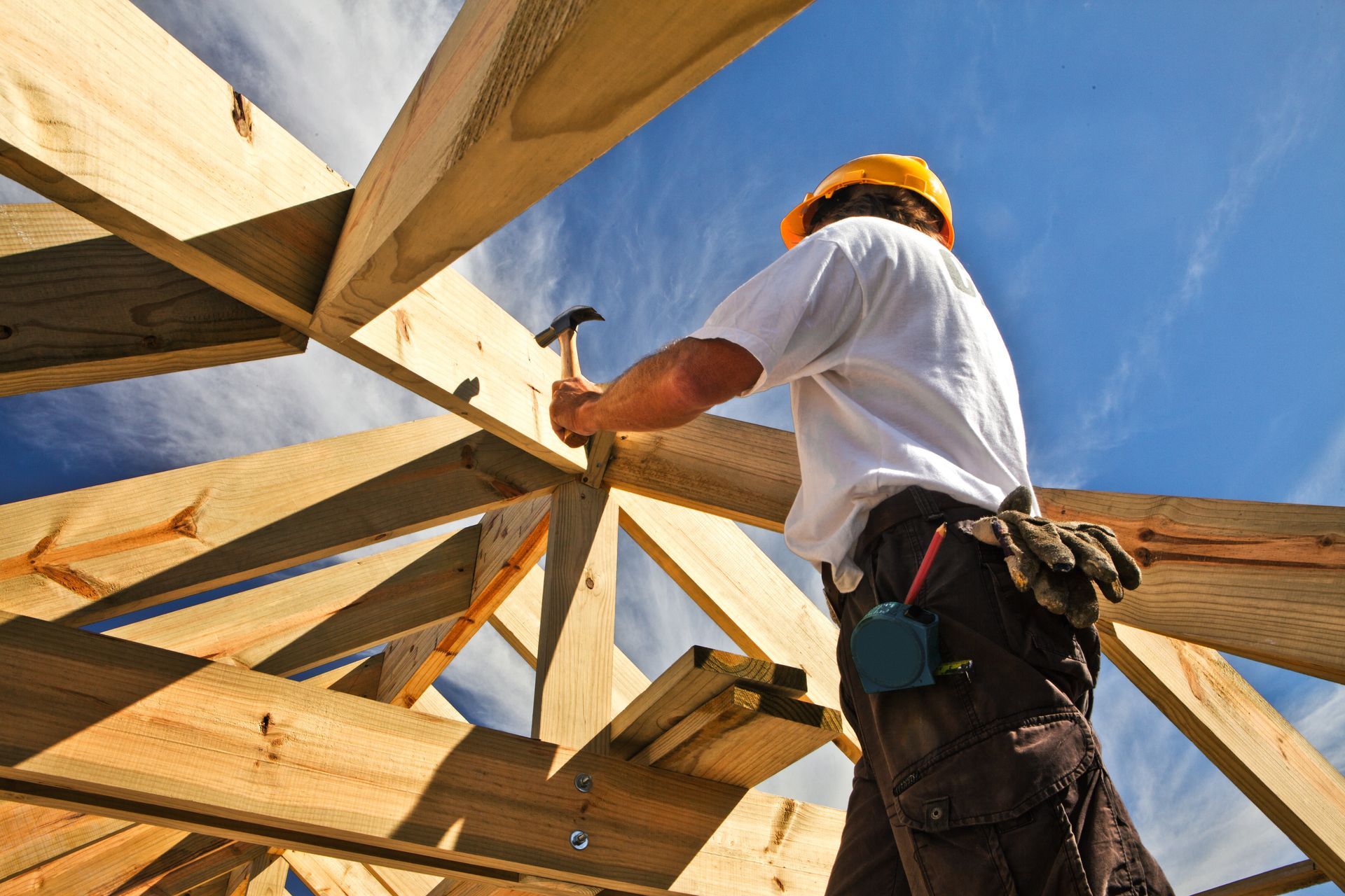 Home worker working on roof structure at construction site.