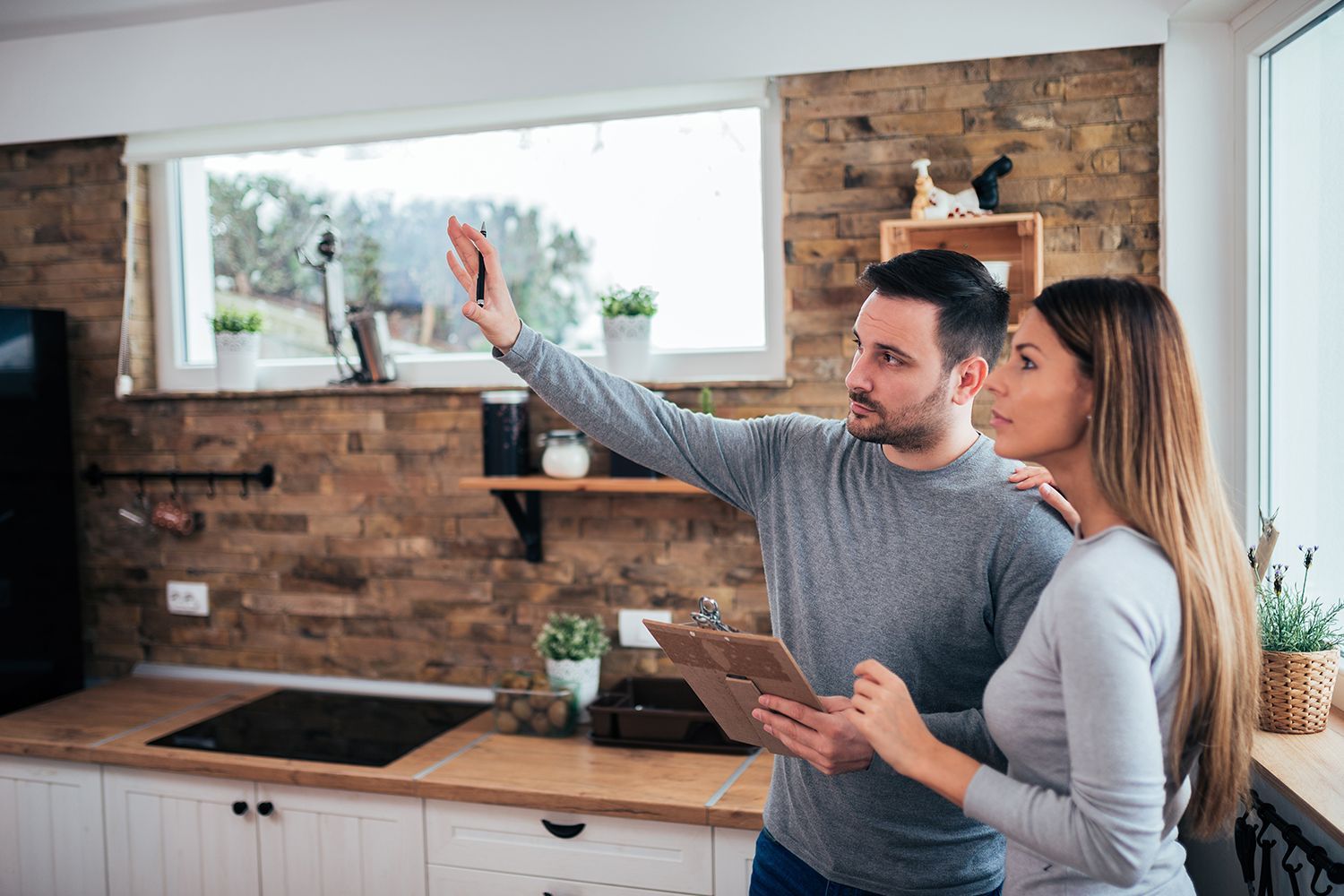 Two people reviewing a tablet while looking around a modern kitchen. Two people reviewing a tablet while looking around a modern kitchen.