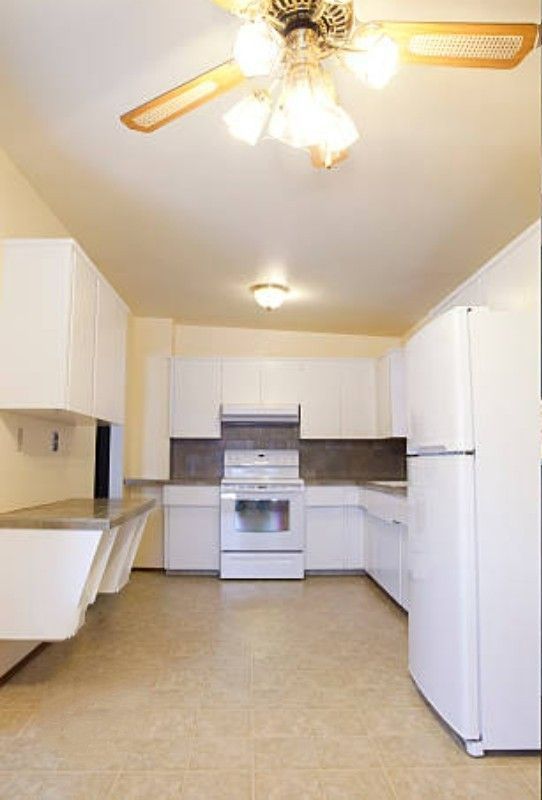White kitchen with matching cabinets, countertops, and appliances. Pale yellow walls and ceiling.