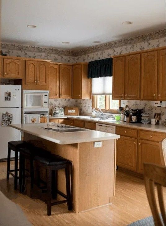 Kitchen with oak cabinets, island with stools, and appliances.