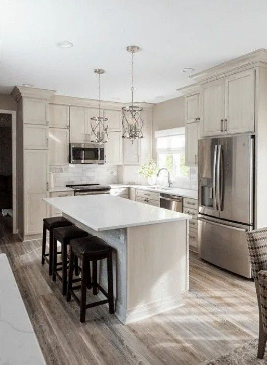 Modern kitchen with island, white countertops, stainless steel appliances, and wood-look flooring.
