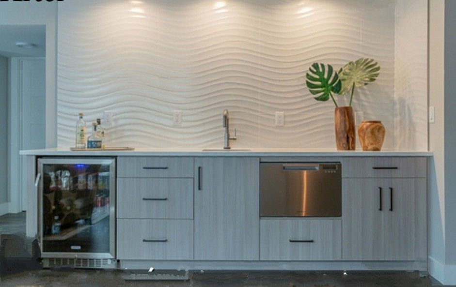 Bar area with white wave wall, gray cabinets, stainless steel appliances, and decor.