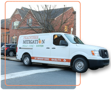 White mitigation services van parked on a street in front of houses, with a person visible in the driver’s seat