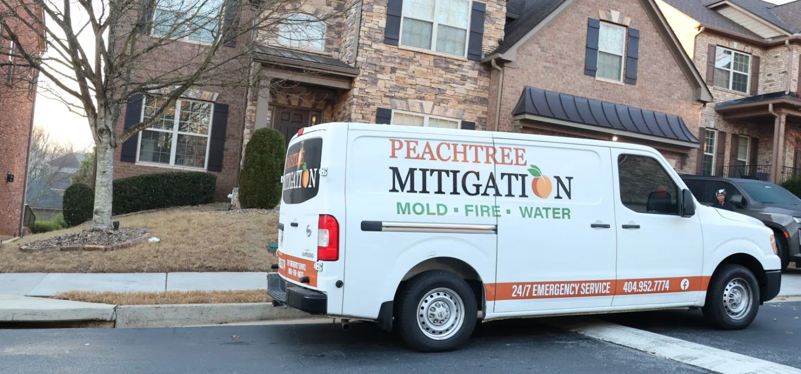 White Peachtree Mitigation van parked on a suburban street near houses and trees.