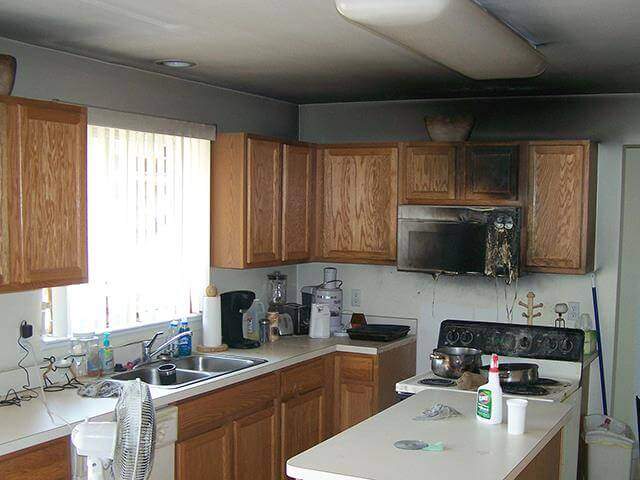 Kitchen with wooden cabinets, white countertops, and a stove beneath a microwave.