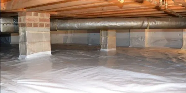Crawlspace with a plastic vapor barrier on the floor, exposed wooden beams, and insulated support posts.