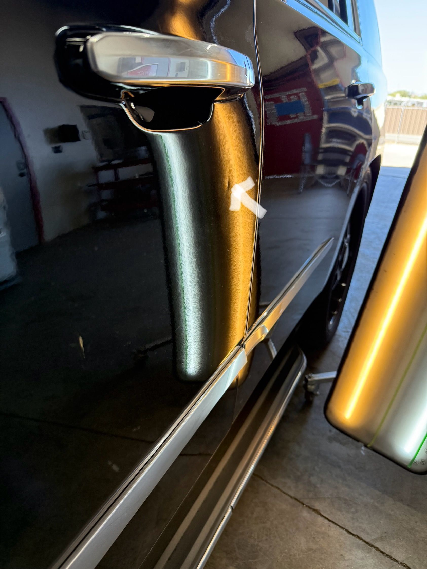 Black car door with a dent, being assessed for repair.