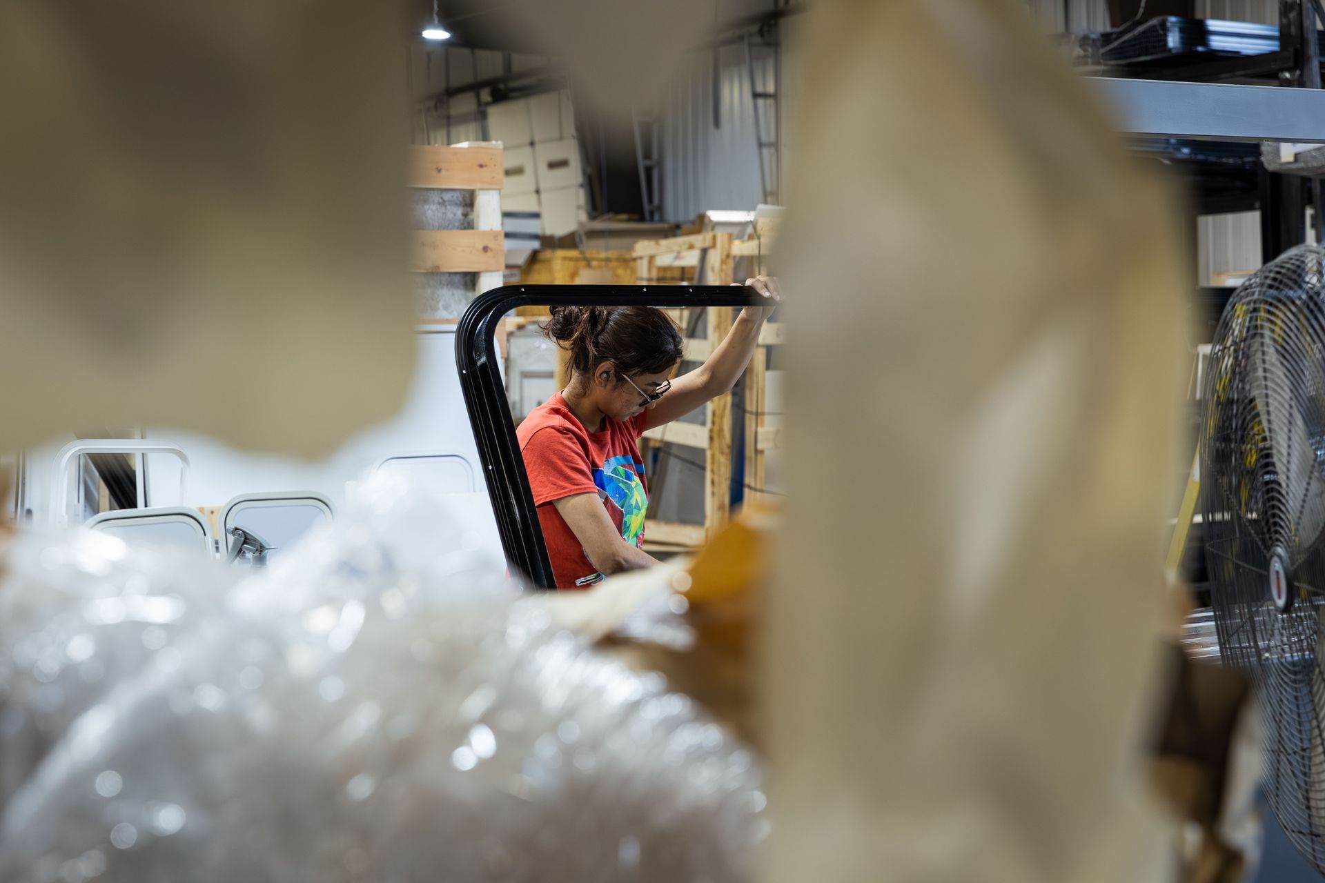 Worker in a warehouse sorting items among shelves and packed materials.