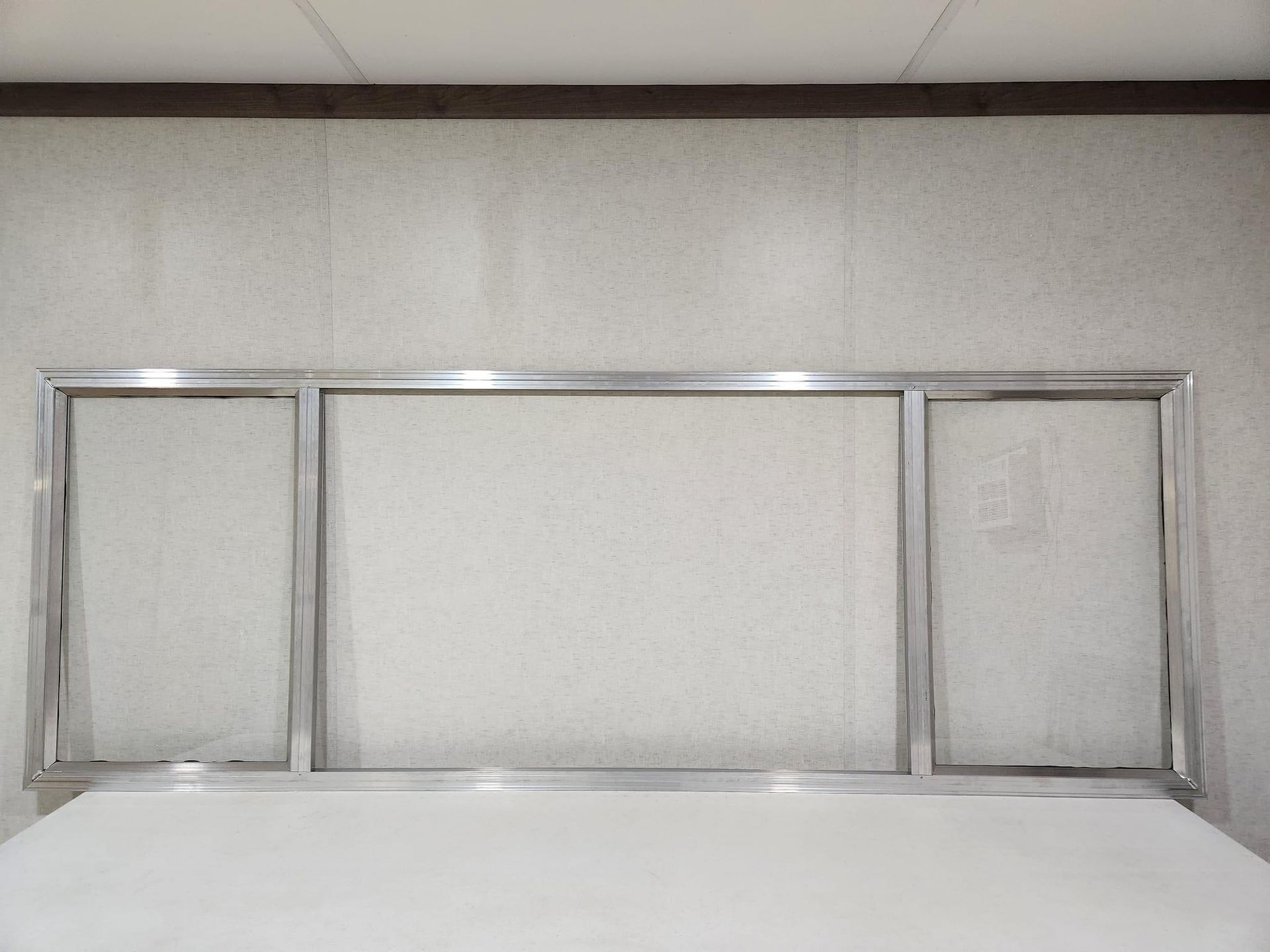 Metal-framed headboard with three rectangular panels behind a white bed in a plain room