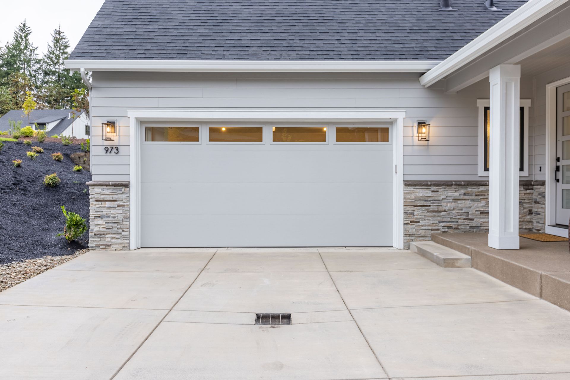 Modern suburban house exterior with a white garage door and concrete driveway
