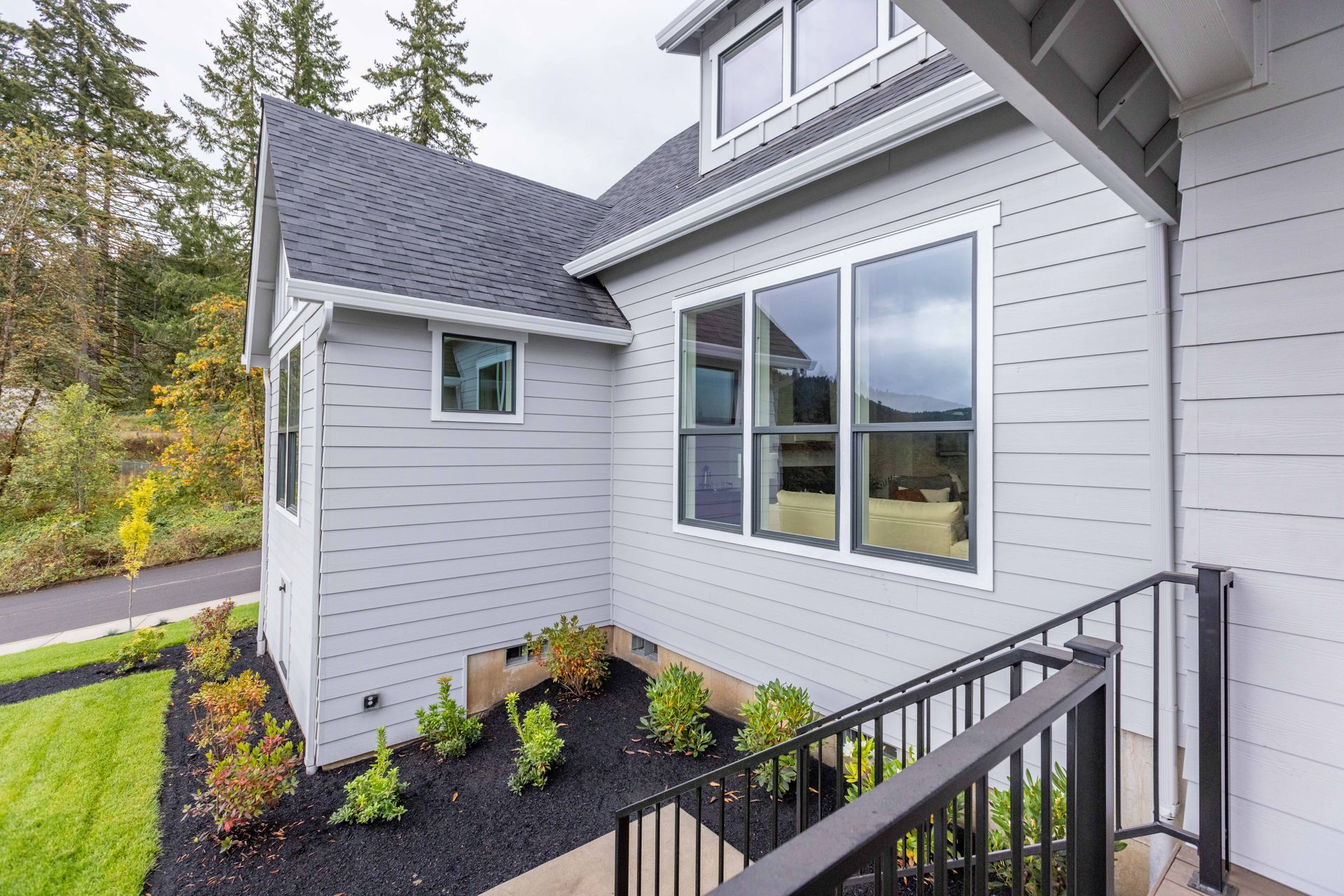 Modern white house exterior with gray siding, large windows, and a small landscaped entry path