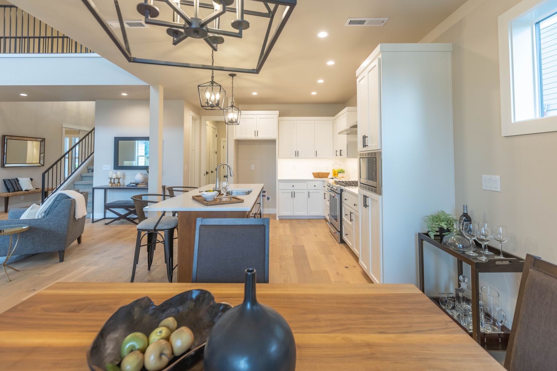 Modern open-concept kitchen and dining area with white cabinets, wood floors, and pendant lighting