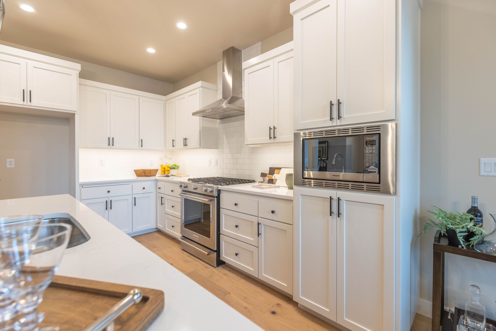 Bright modern white kitchen with stainless appliances, island, and wood flooring