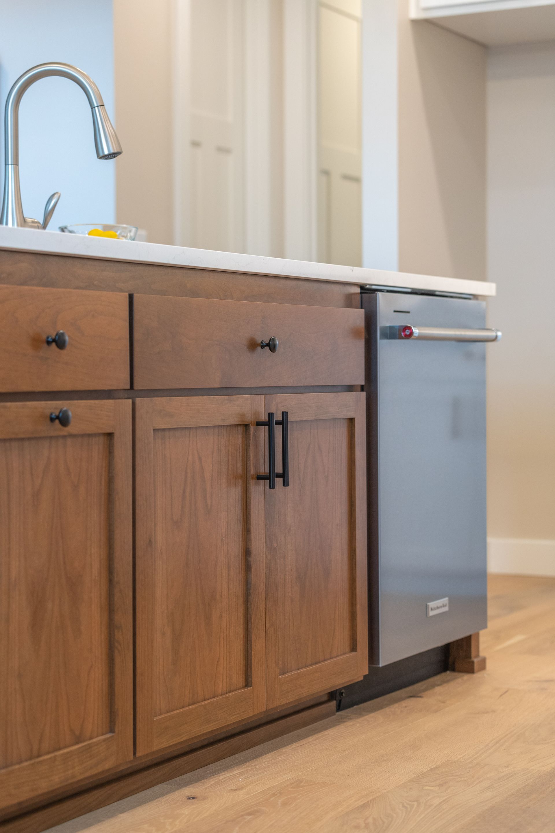 Kitchen with wooden cabinets, light countertop, chrome faucet, and a stainless dishwasher