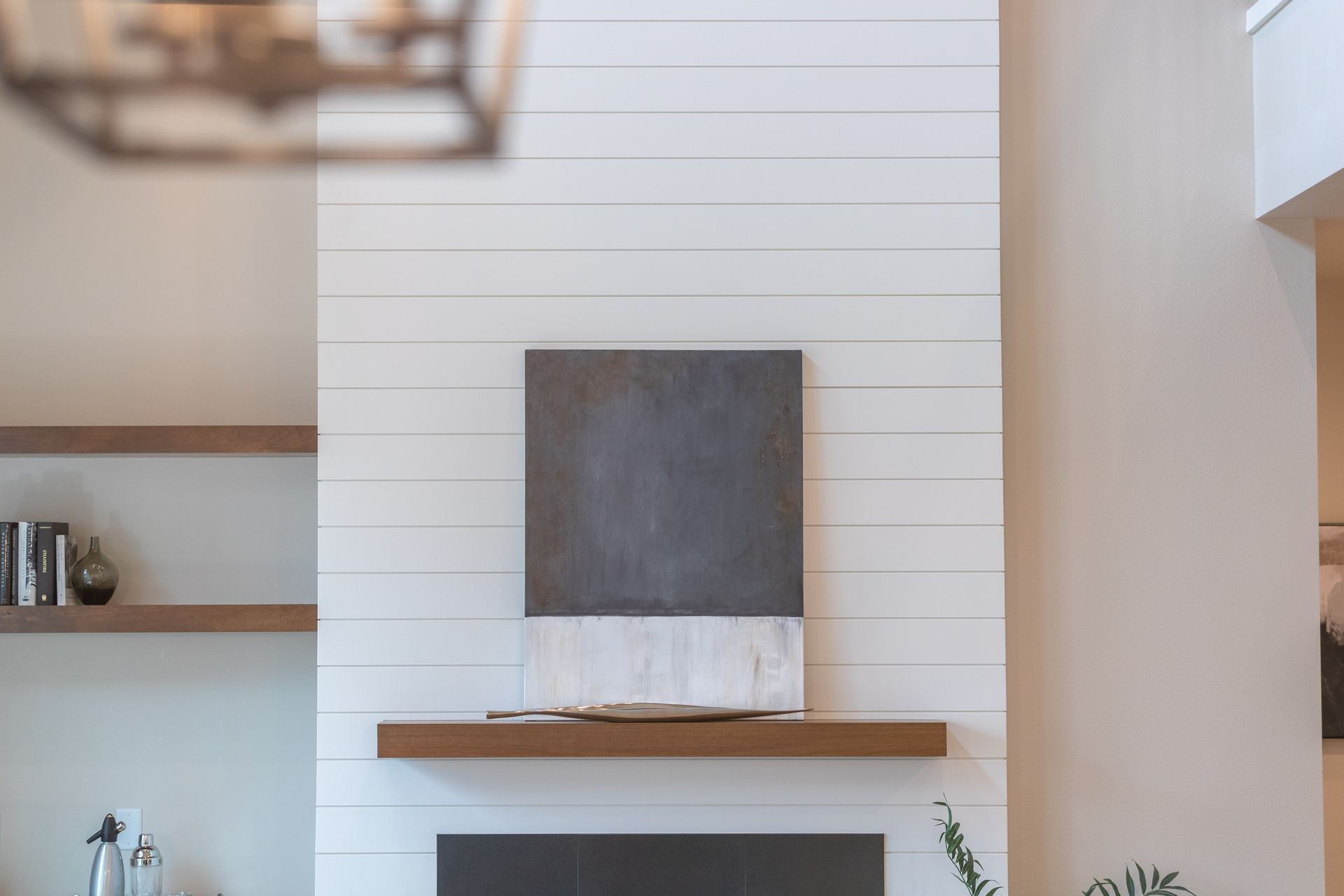 Modern white fireplace with wooden mantel and dark abstract art in a bright room