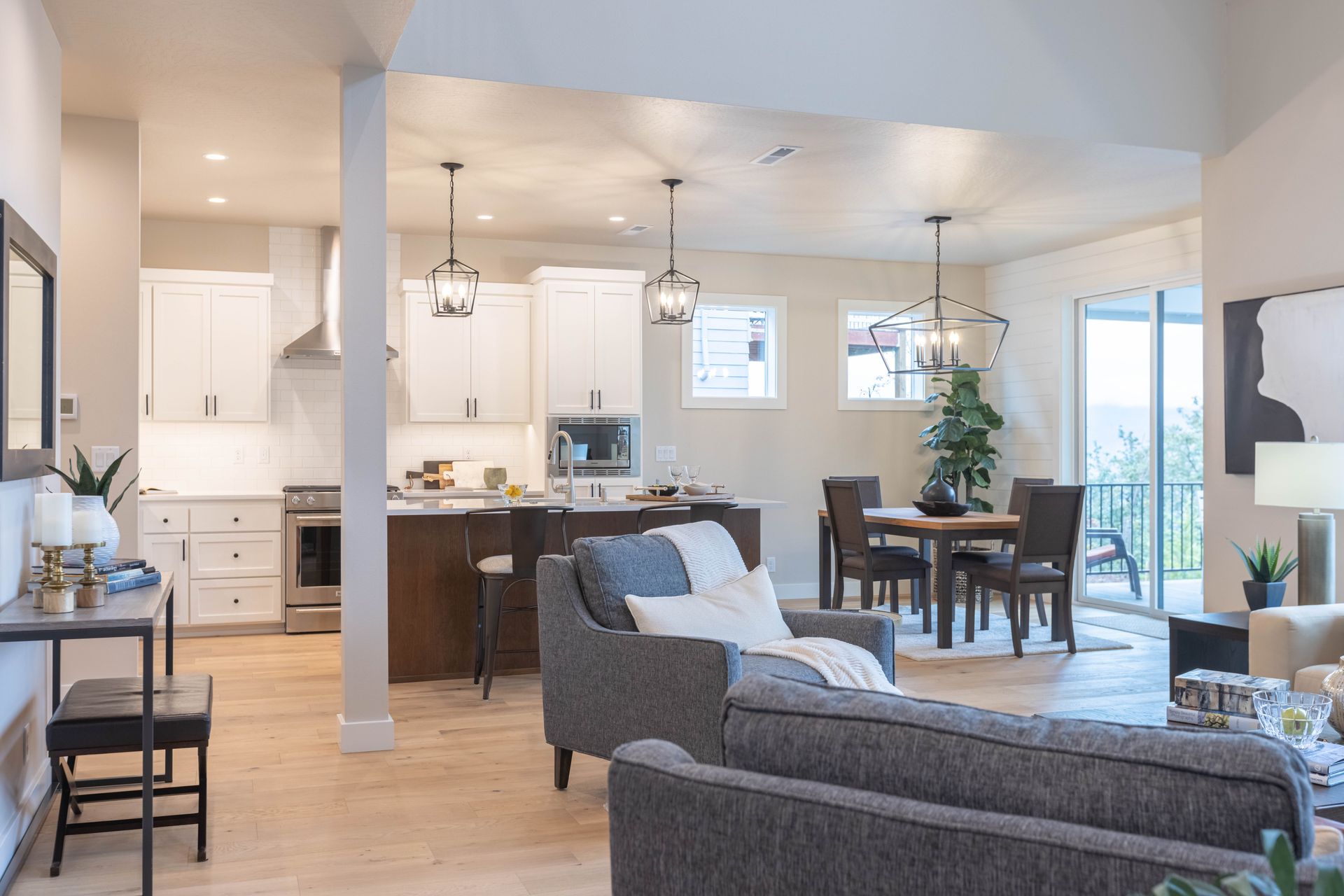 Open-plan living room and kitchen with gray sofa, dining table, and bright white cabinets