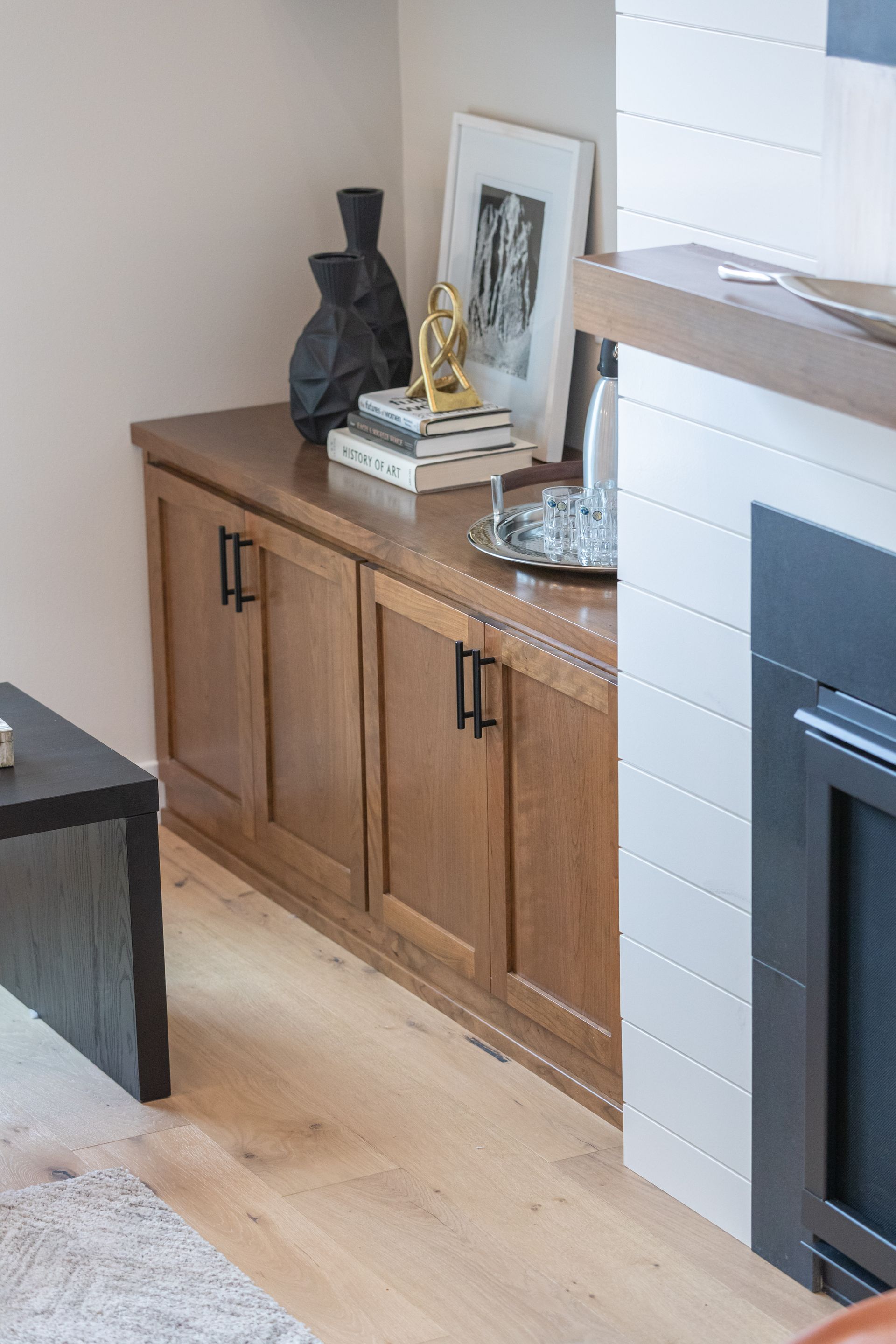 Wooden cabinet with decor beside a fireplace in a bright living room