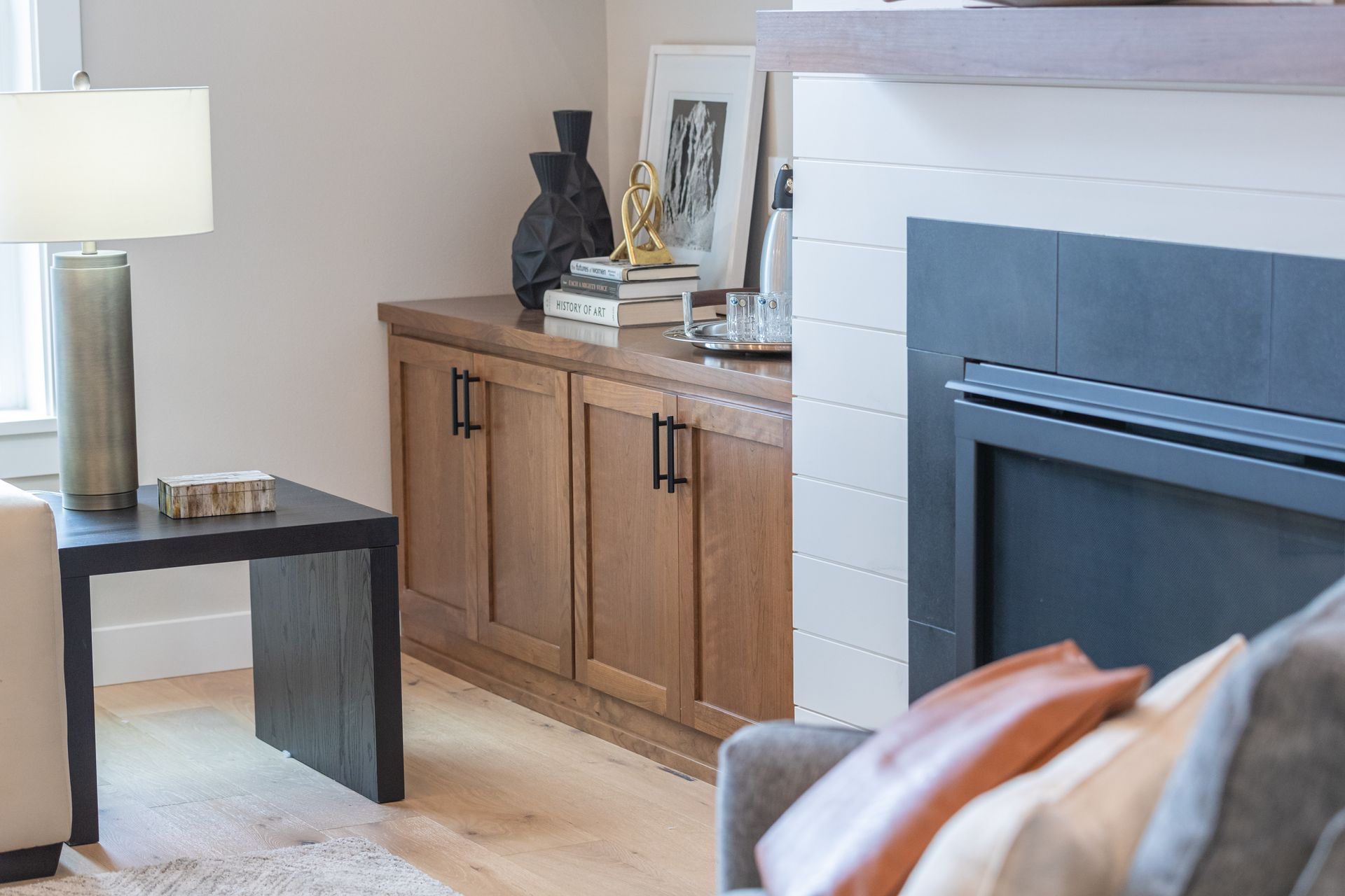 Modern living room with fireplace, wooden cabinet, and lamp on a dark side table