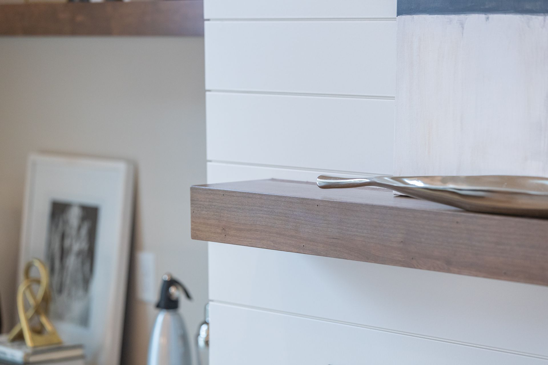 Kitchen shelf with stacked white boxes, a wooden ledge, and a framed photo in the background