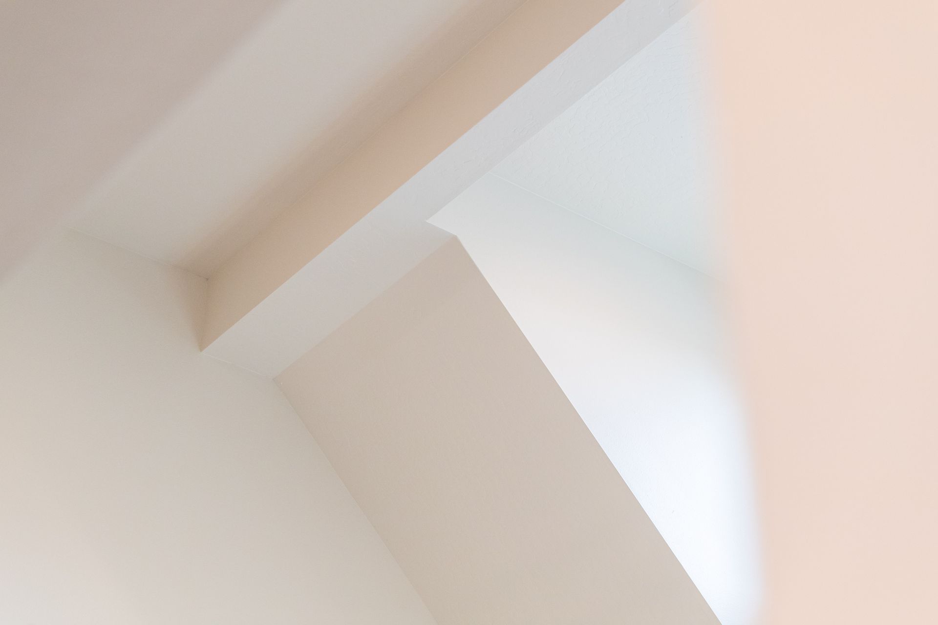 Close-up of a white ceiling corner with angular beams and soft light from a skylight