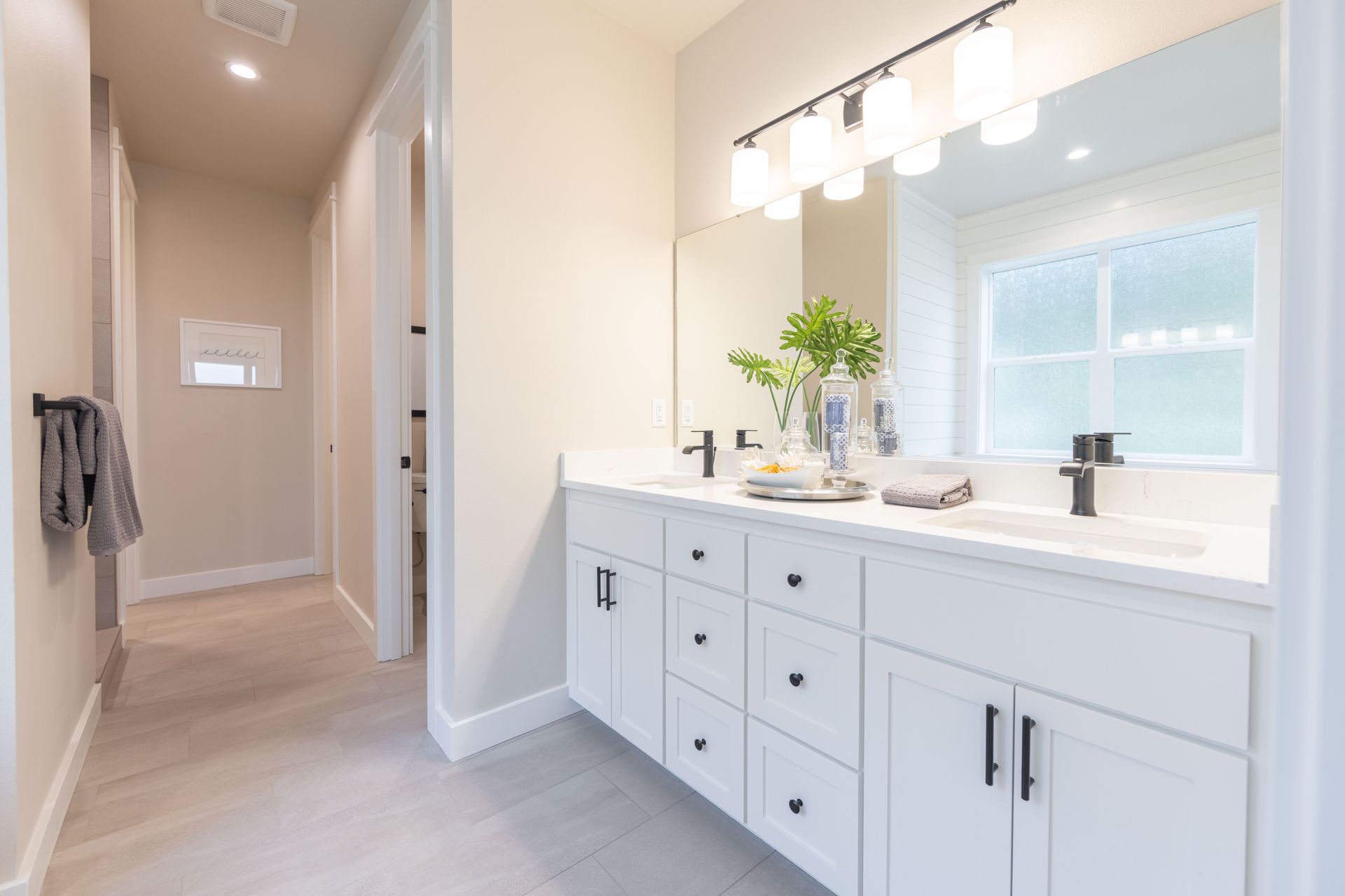 Bright white bathroom vanity with mirror, sink, and chrome fixtures in a clean hallway setting