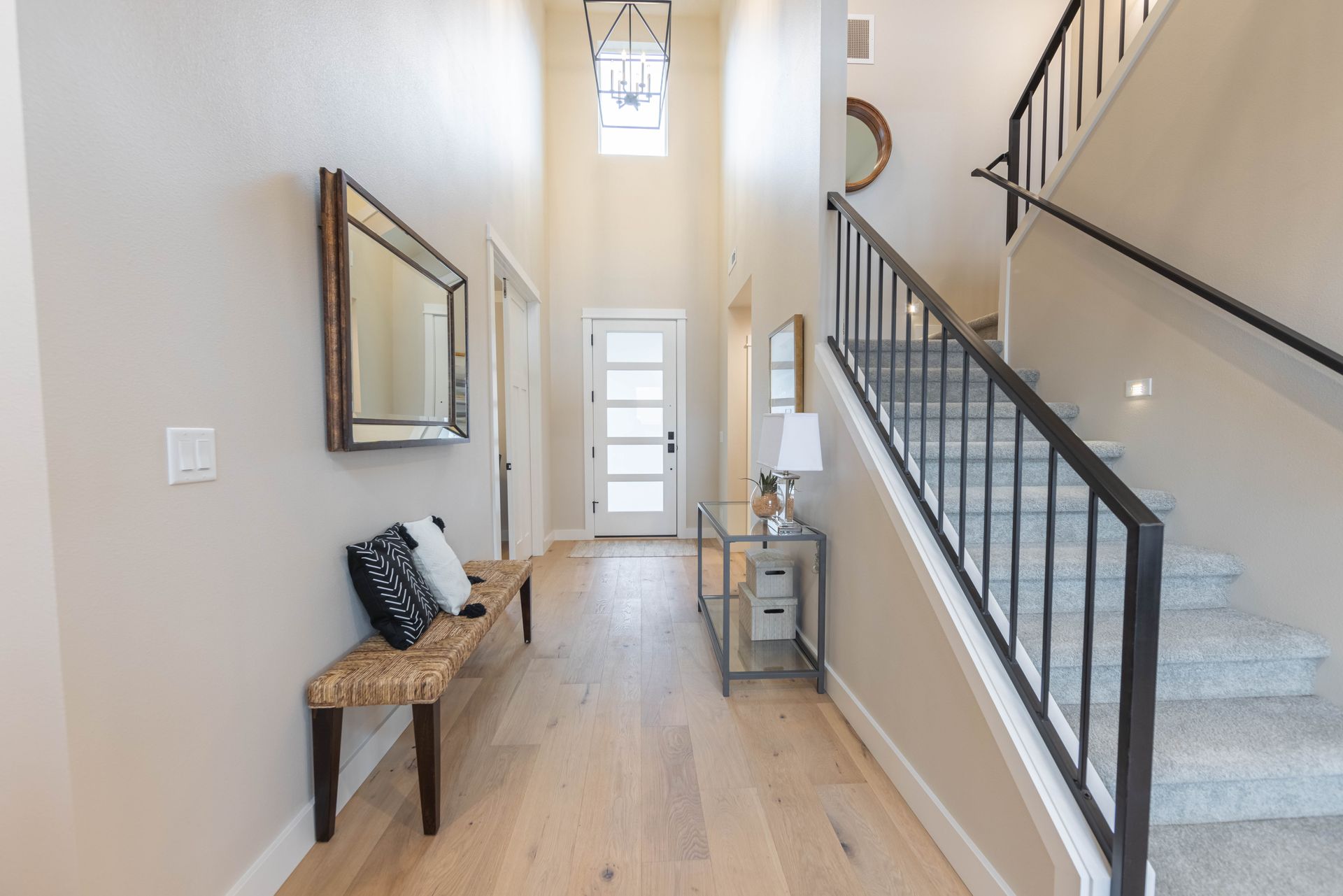 Bright hallway with staircase, bench, mirror, and front door in a modern home.