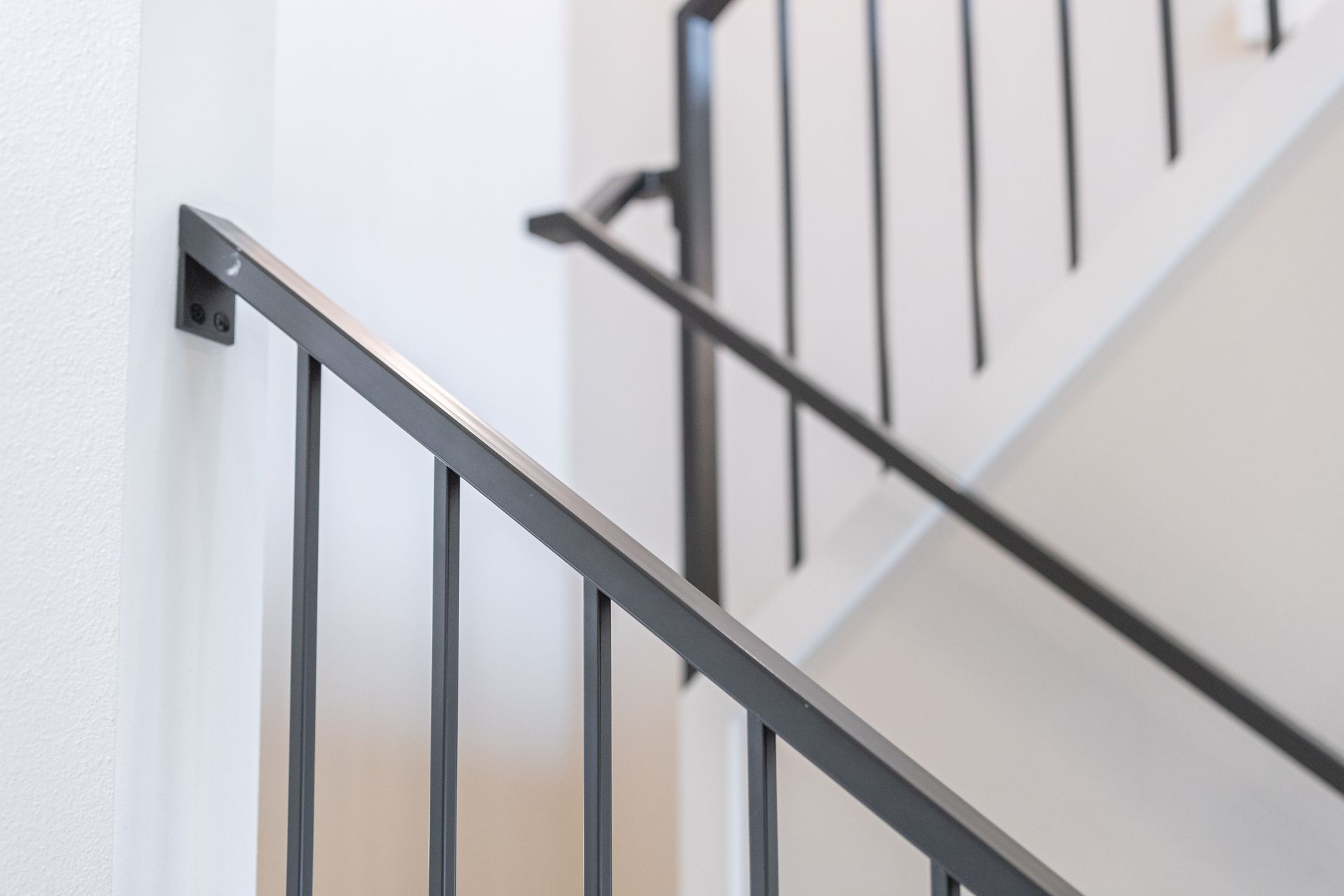 Black metal stair railings along a white staircase wall