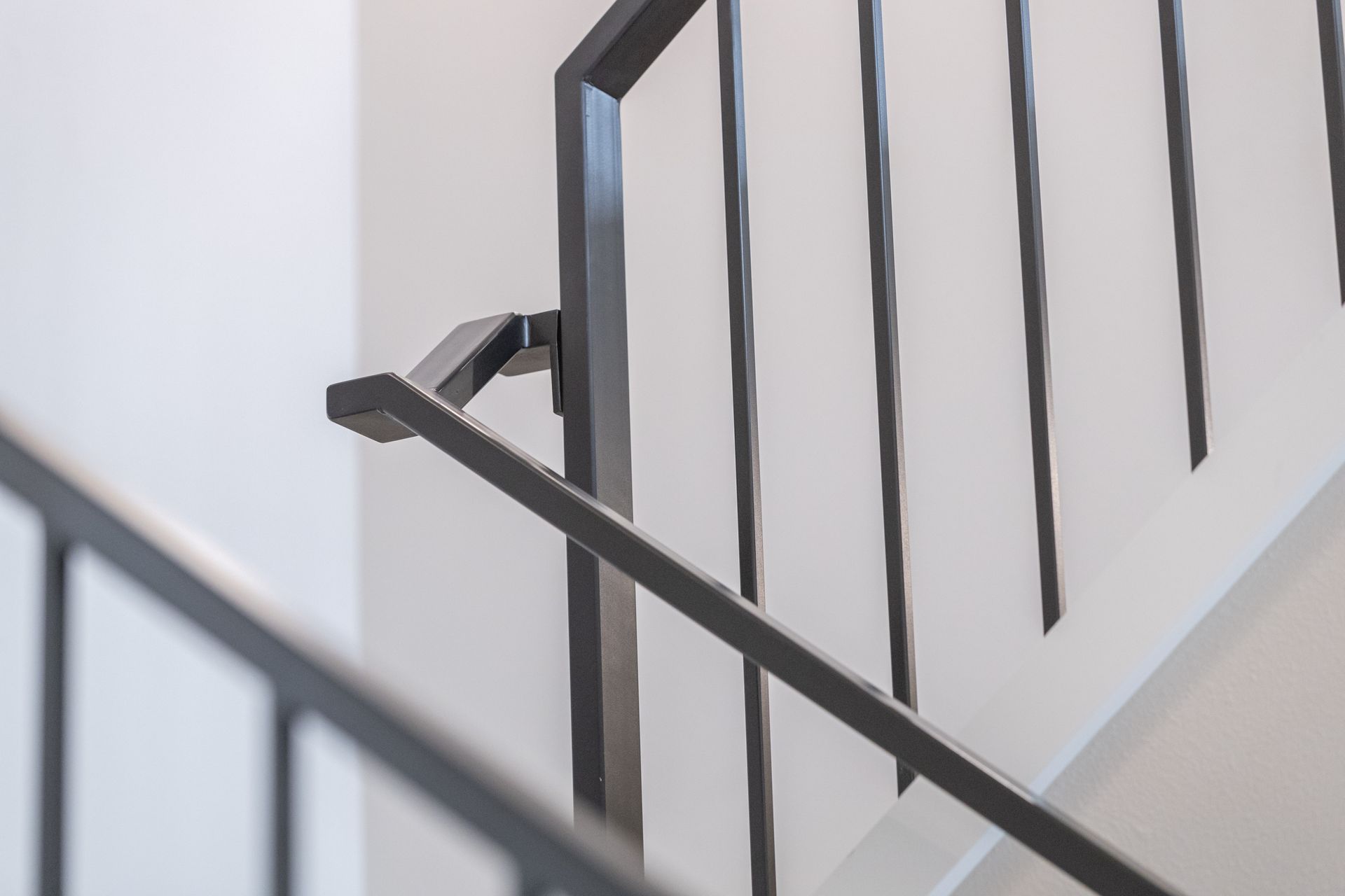 Black stair railing with vertical bars in a bright indoor stairwell