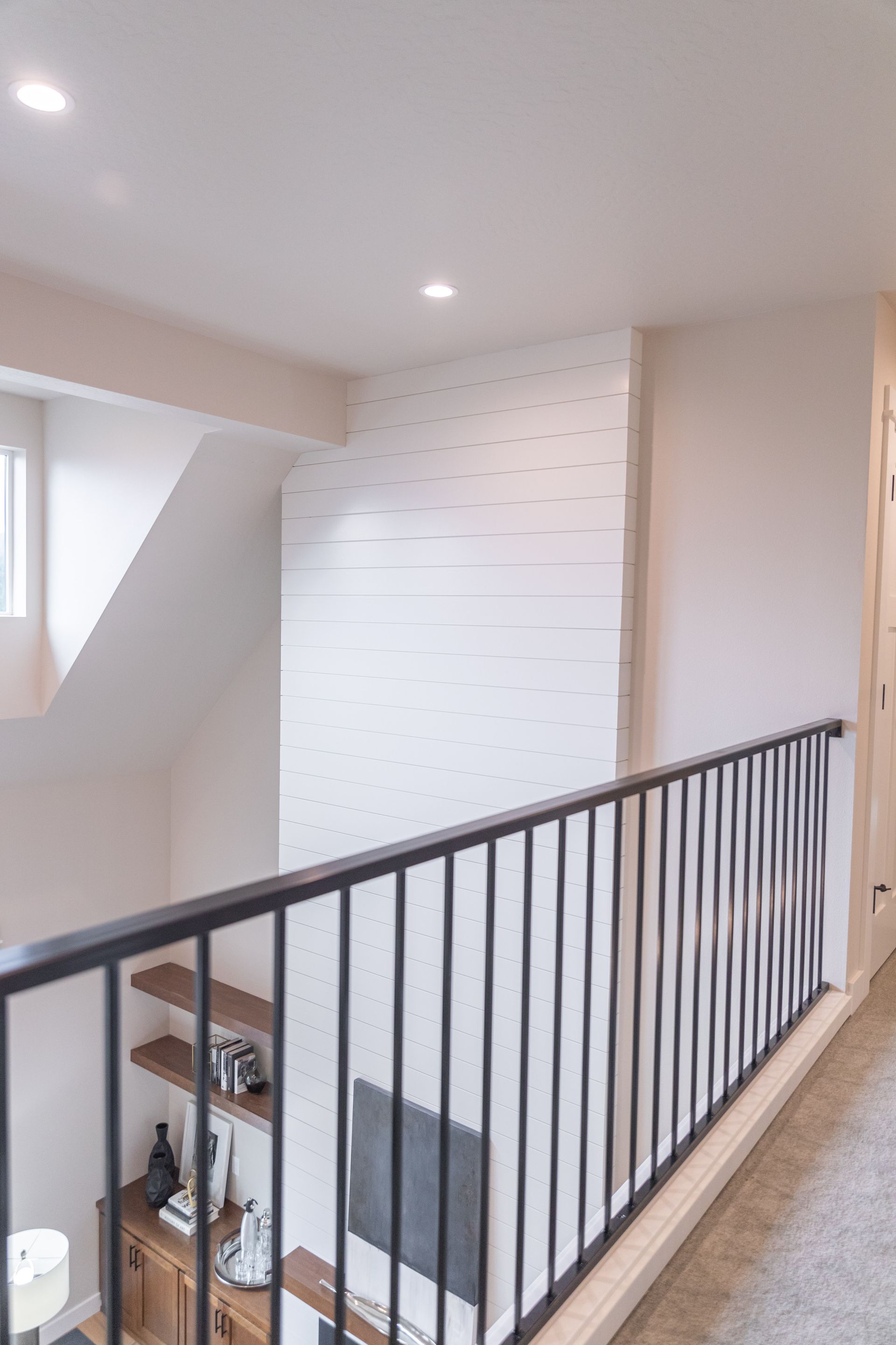 Stair landing with black railing, white walls, skylight, and a small window.