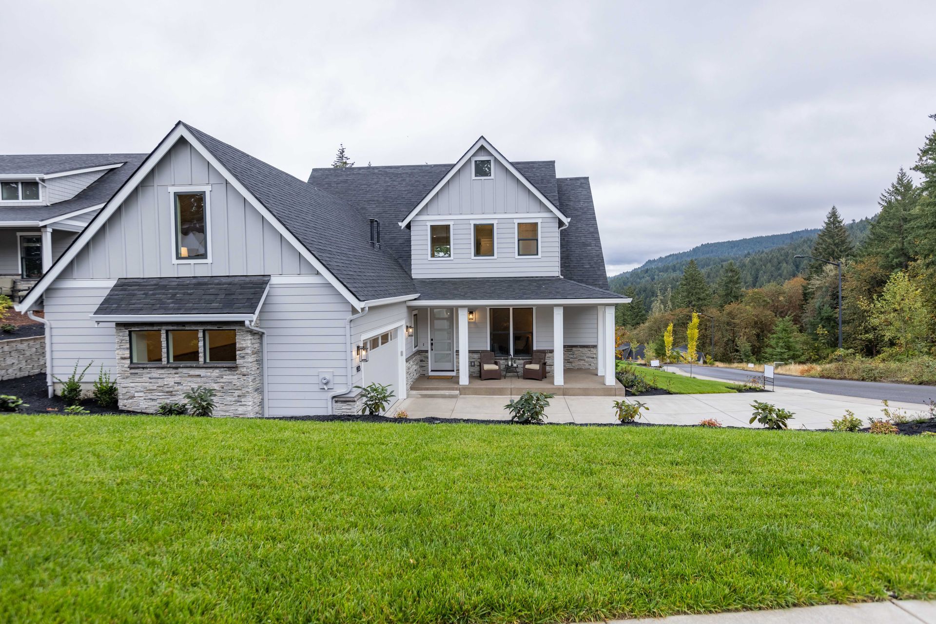 White two-story house with gray roof and large green lawn in a suburban neighborhood