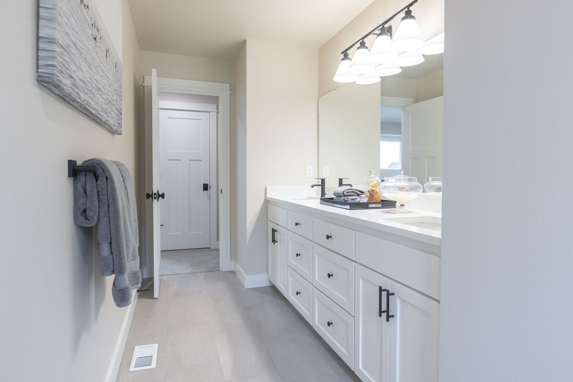 Bright modern bathroom with double vanity, large mirror, and white walls and cabinets