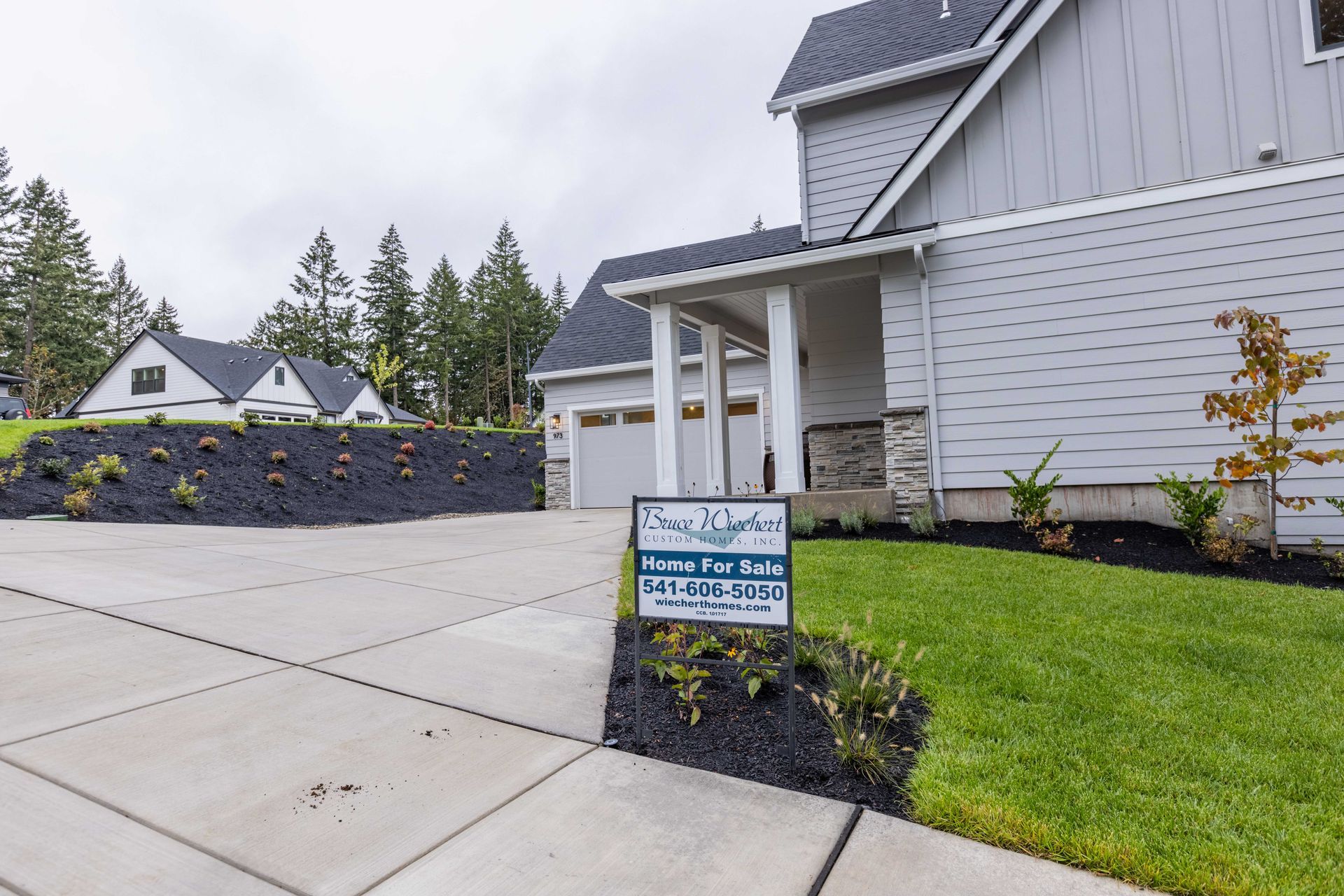 House exterior with driveway, front lawn, and a yard sign in a suburban neighborhood