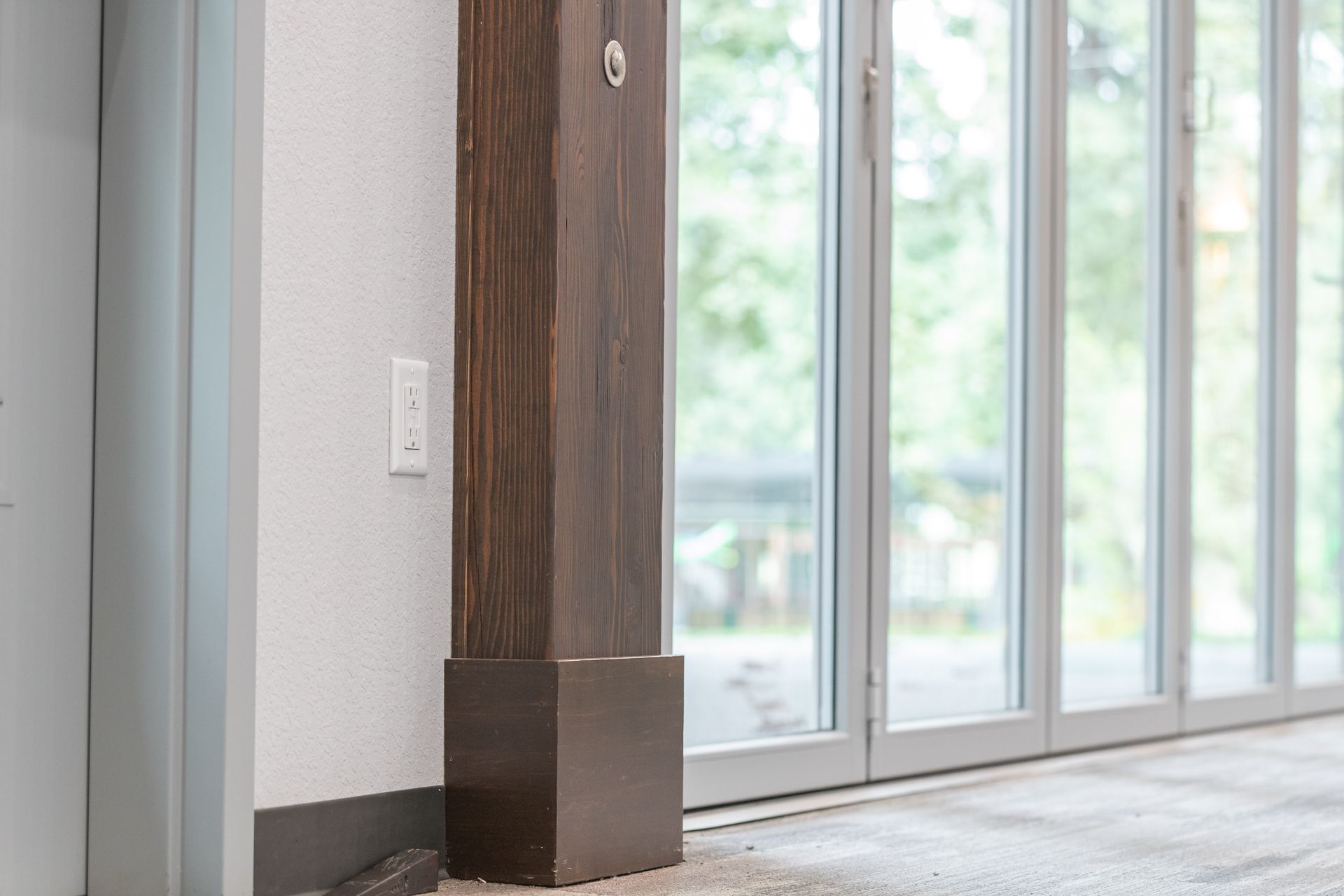 Empty modern room with wood column and large windows overlooking greenery