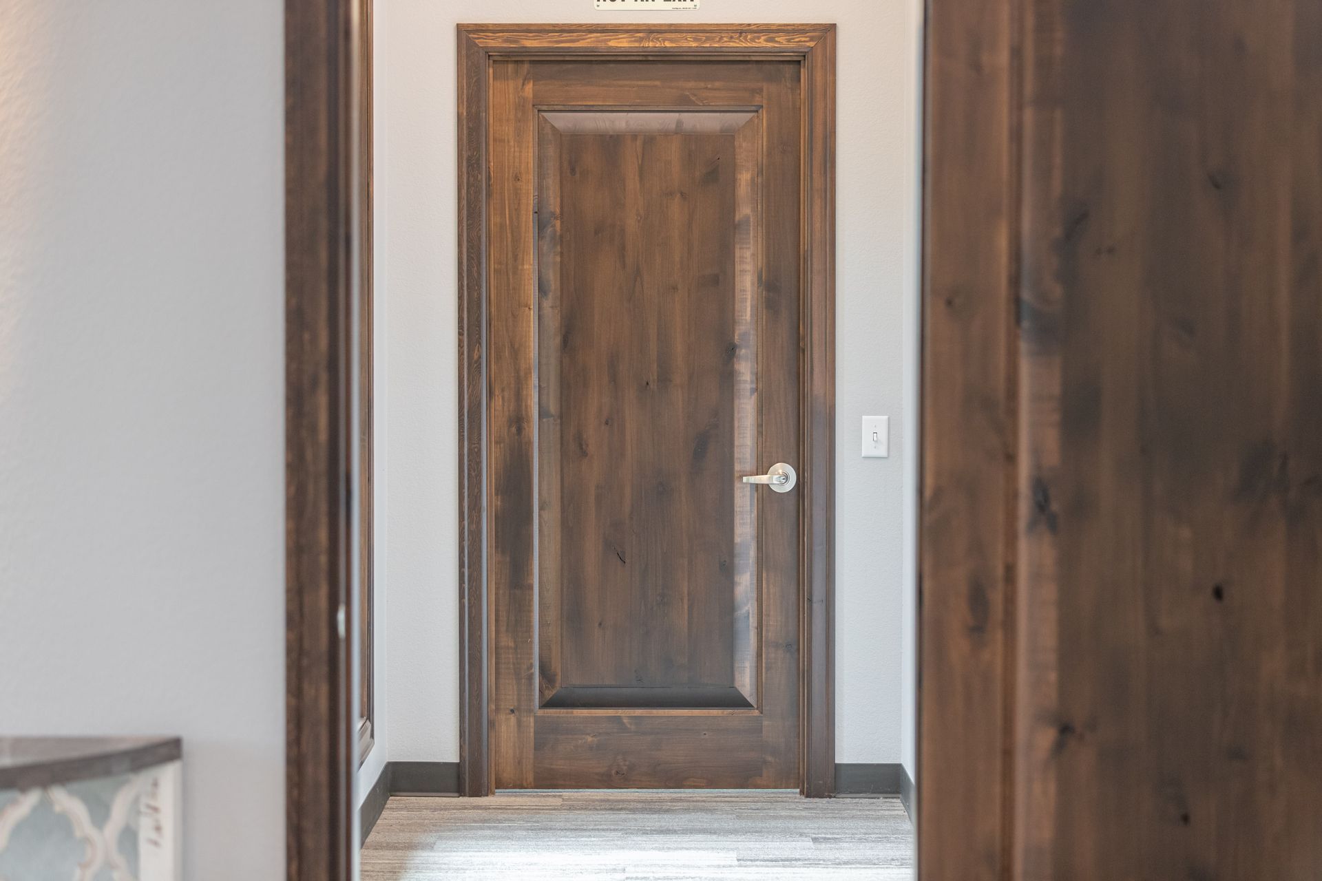Wooden interior door in a hallway with white walls and light tile floor