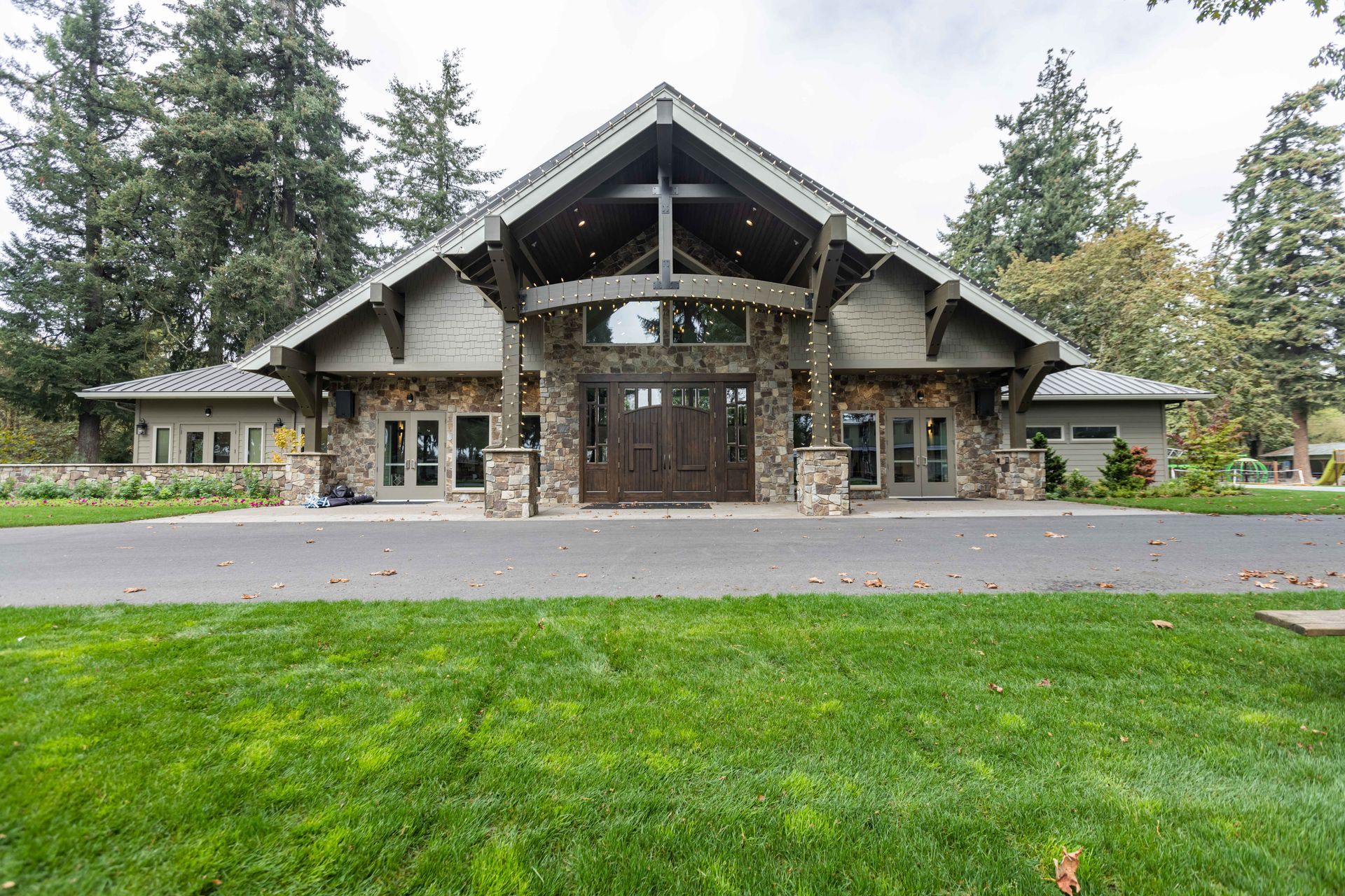 Large rustic lodge with stone and wood facade, centered entrance, and green lawn in front