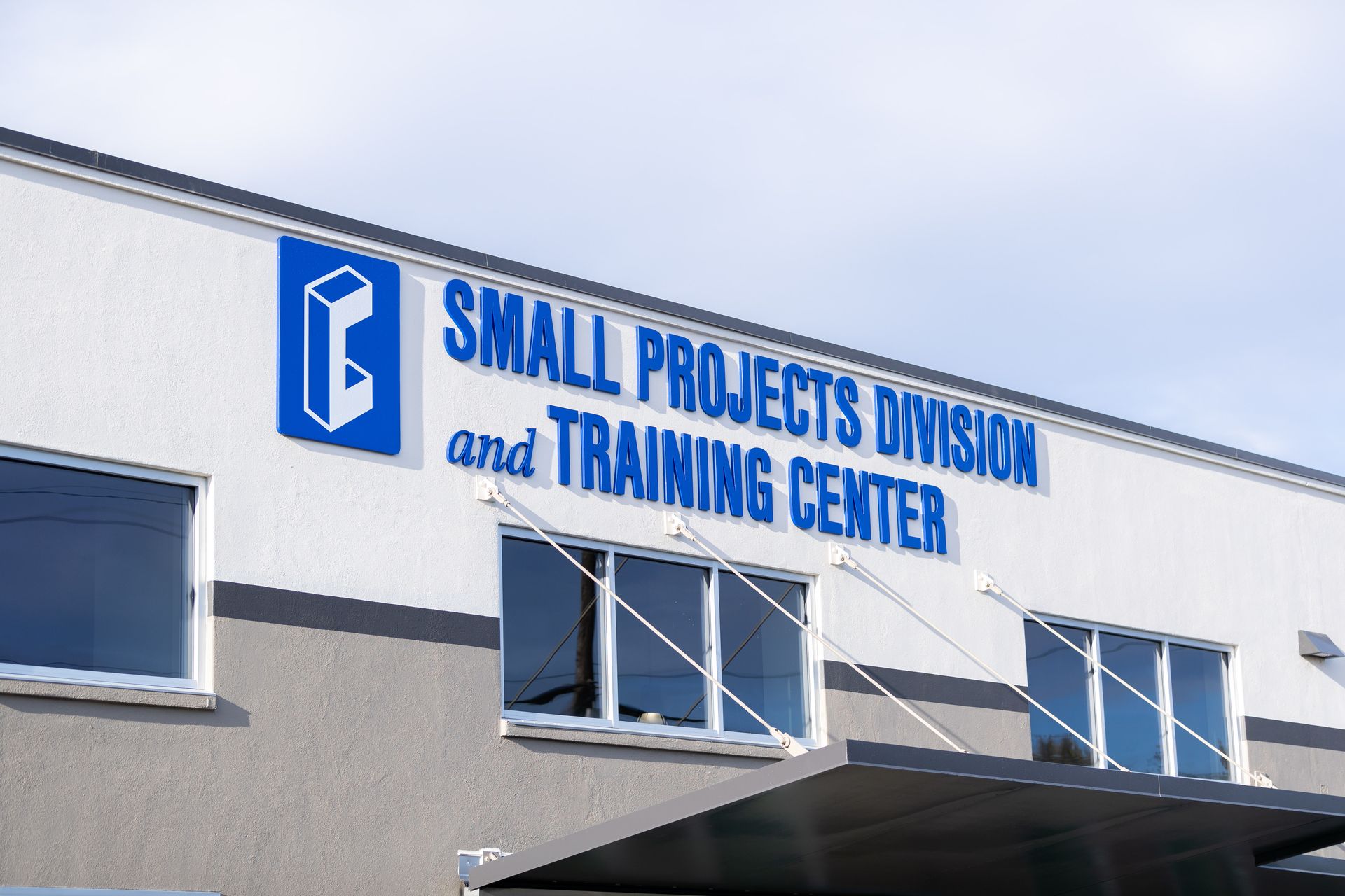Blue sign reading “Small Projects Division and Training Center” on a building facade