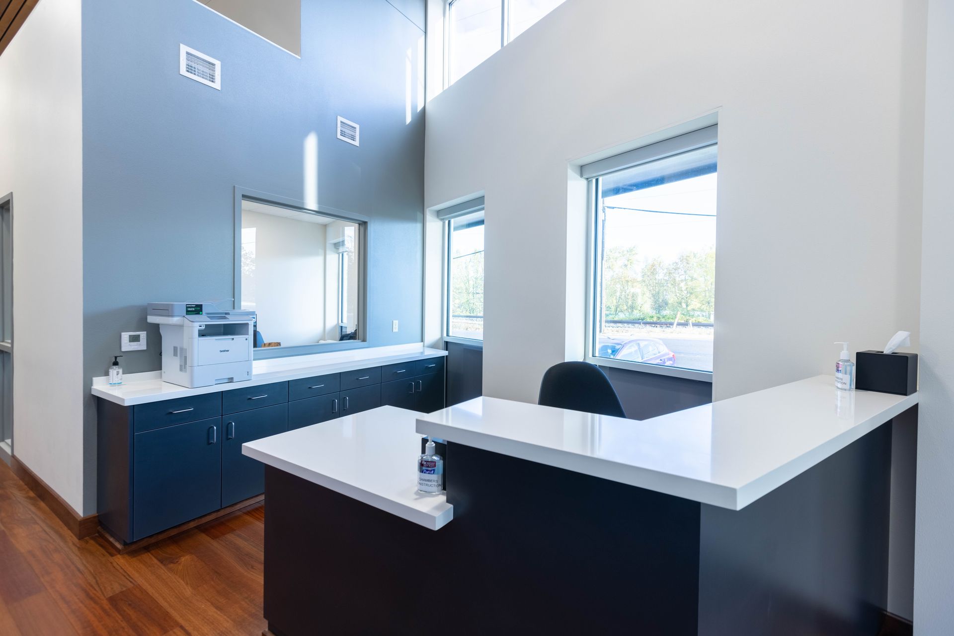 Modern reception desk in a bright, minimalist office lobby with white walls and wood flooring