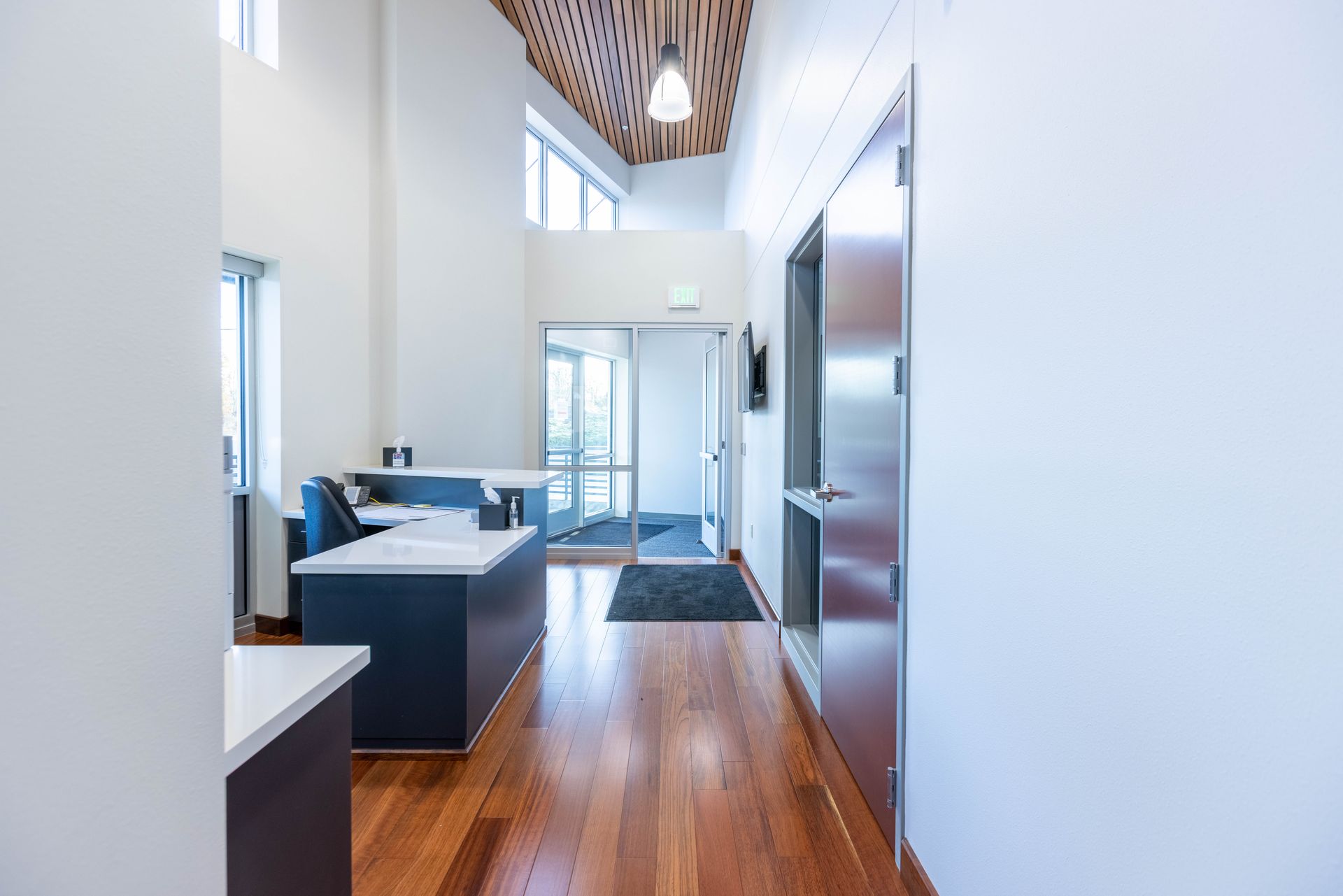 Modern bright hallway with wood floors, white walls, and a bathroom vanity visible on the left