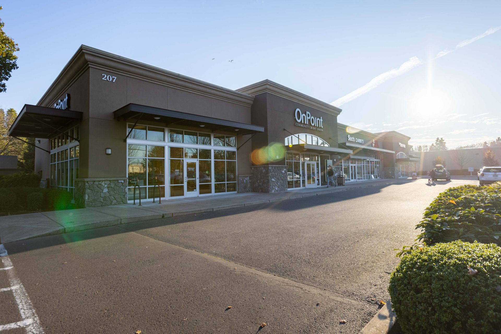 Sunlit storefront with large windows and parking lot in front
