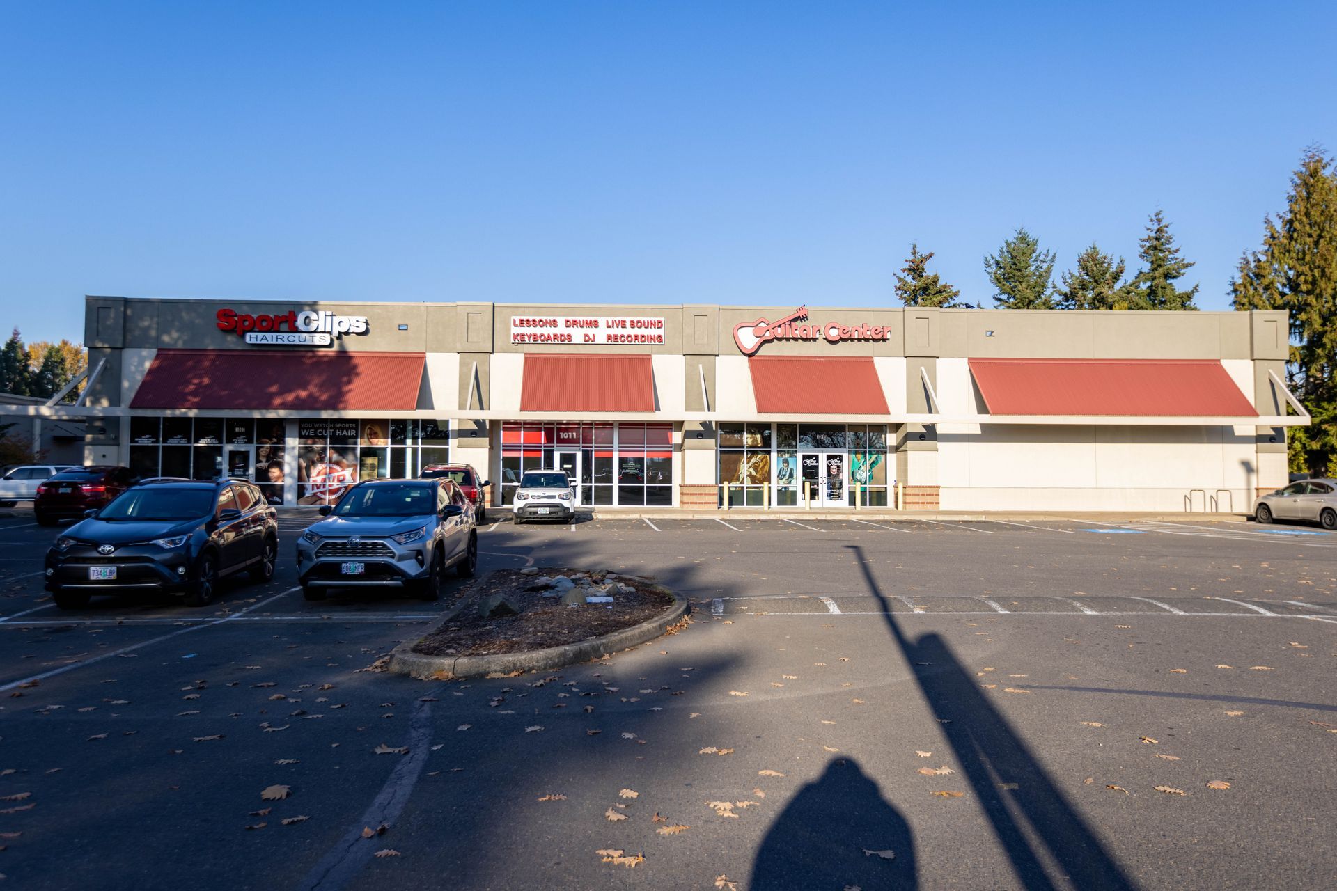 Strip mall storefronts with parked cars in front on a sunny day