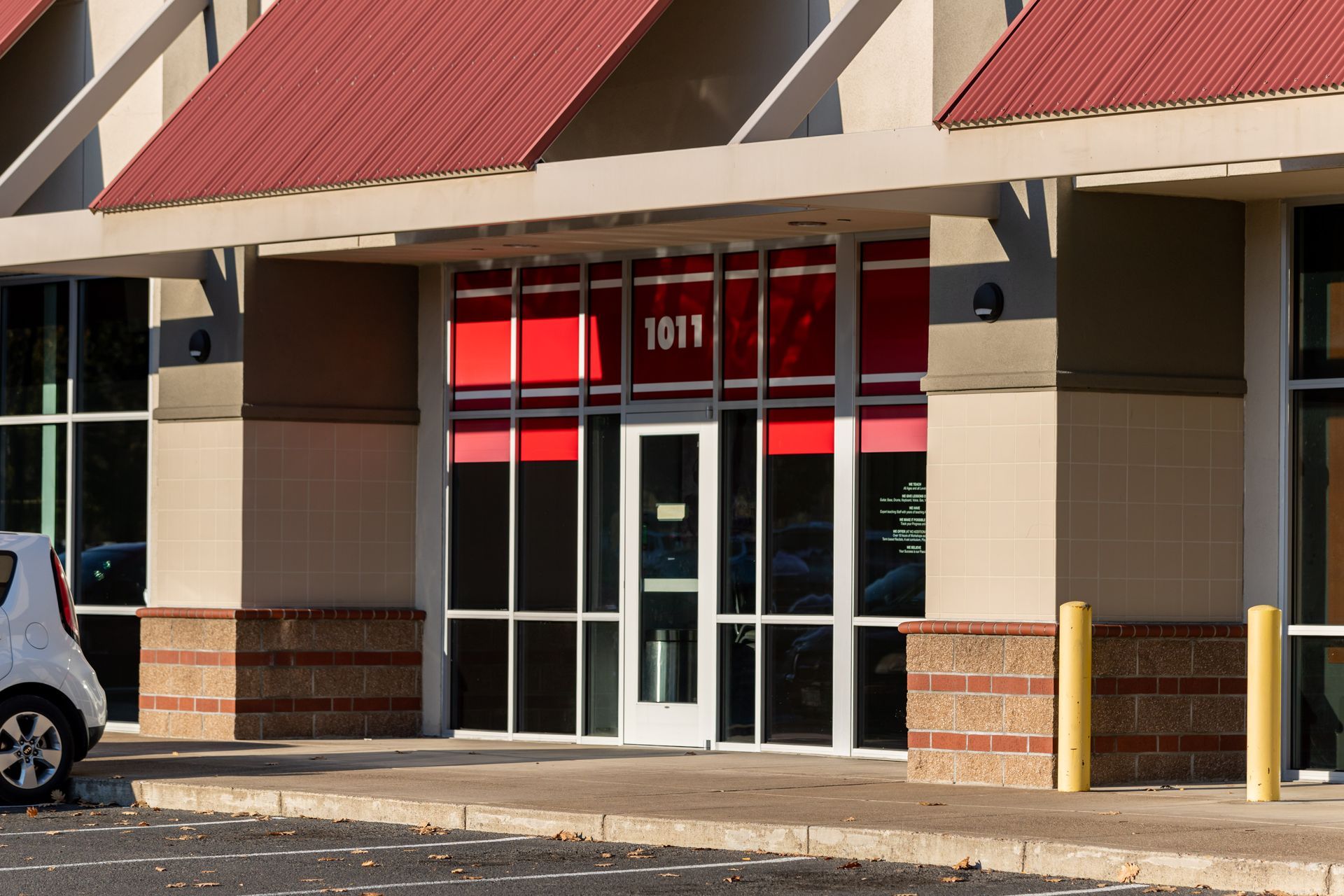 Storefront entrance with glass doors, red awning, and tan brick facade