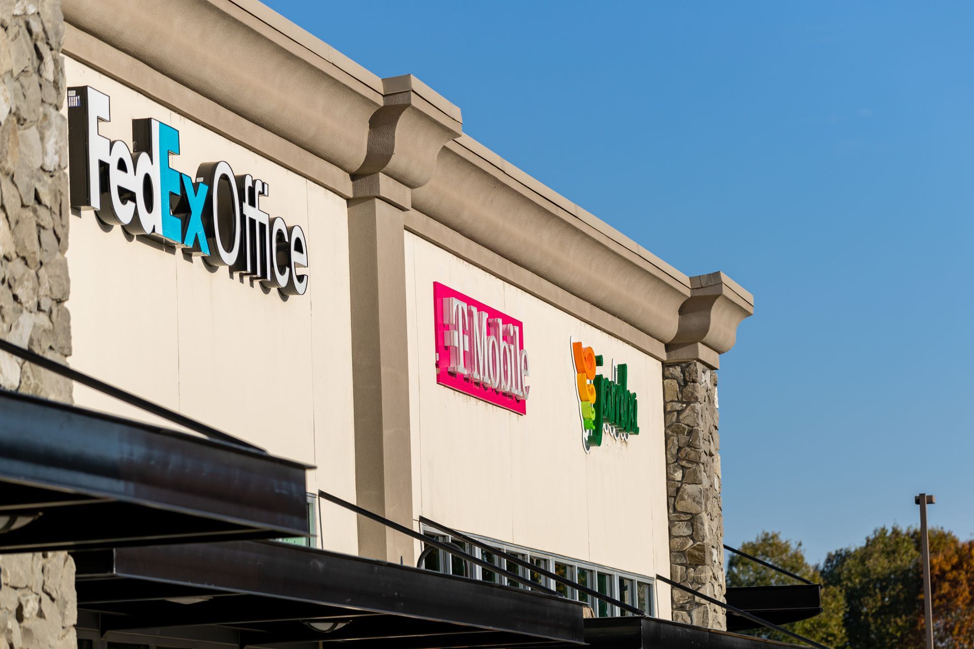 Retail storefront with colorful signs on a beige building under a blue sky