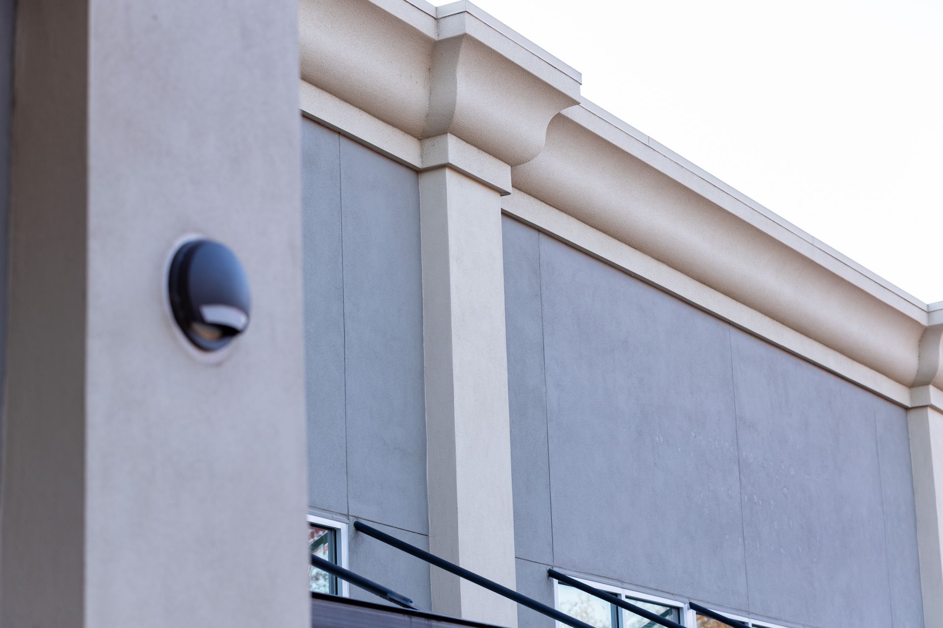 Exterior wall of a building with a mounted black light fixture and decorative trim.