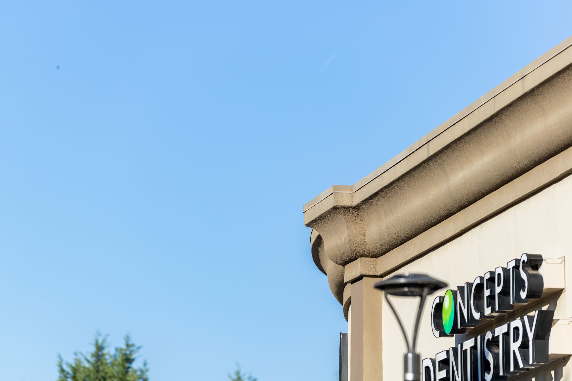 Dental office sign on a beige building against a clear blue sky