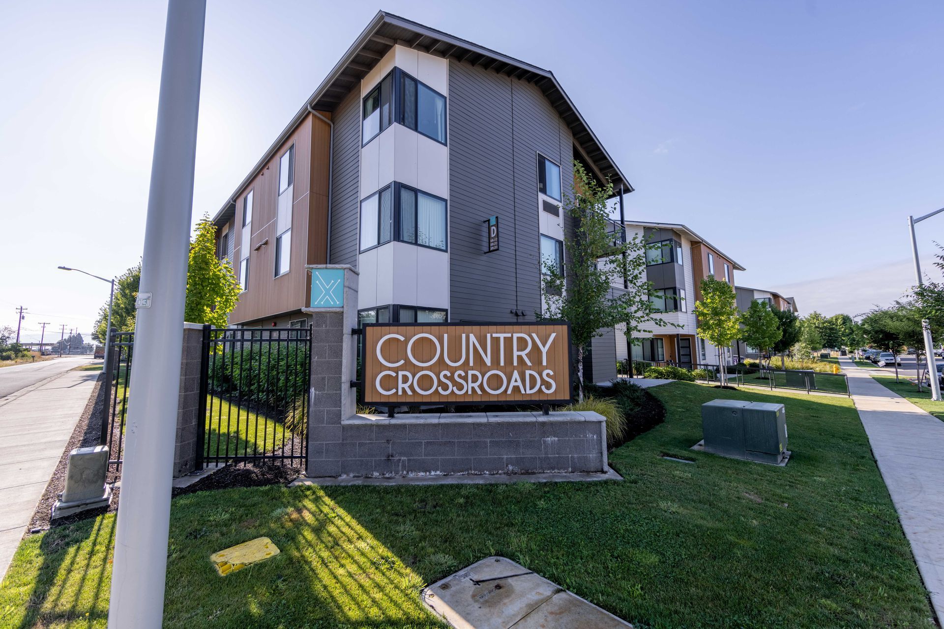Country Crossroads apartment building sign beside a sidewalk and street