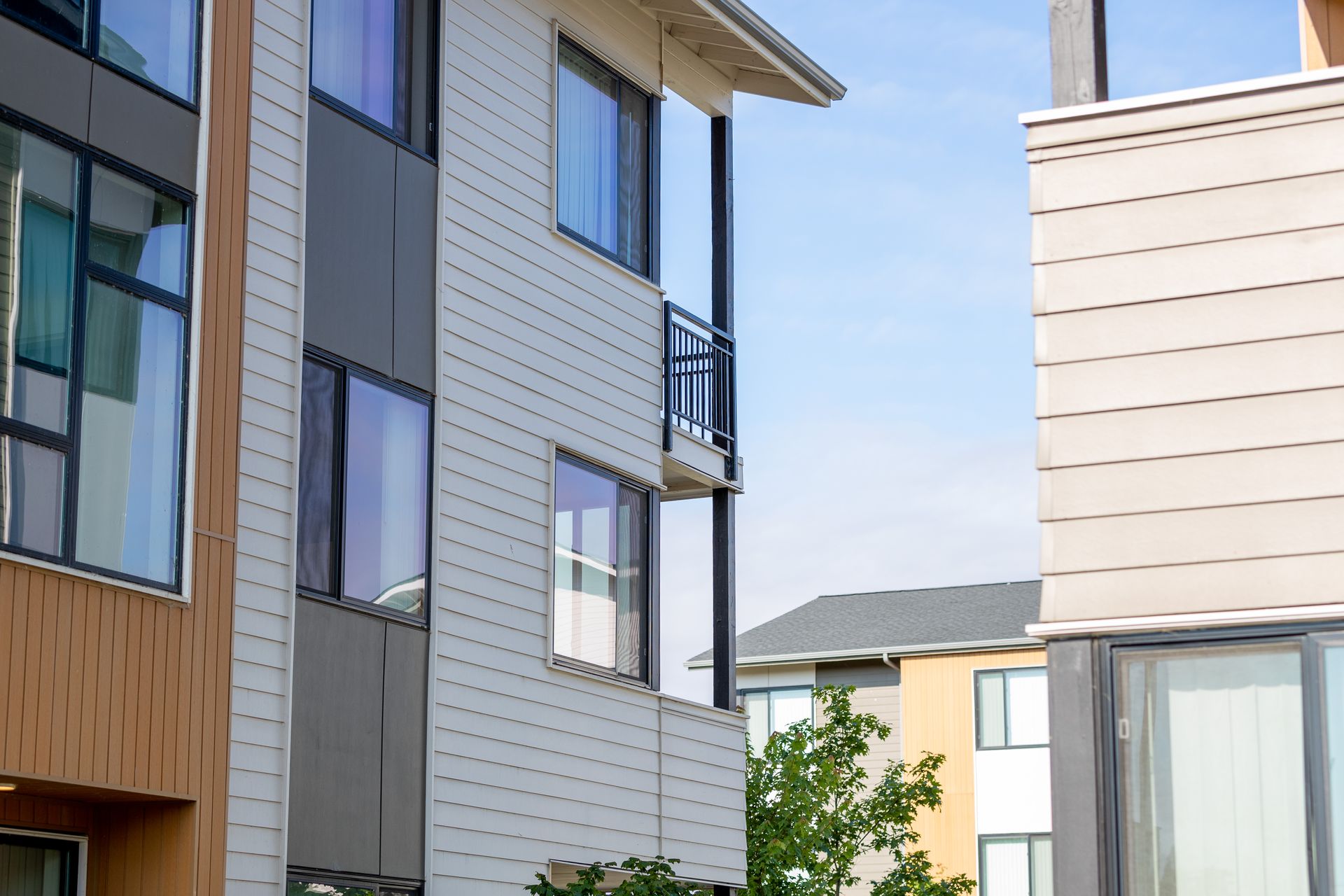 Modern apartment buildings with white siding and balconies under a clear blue sky